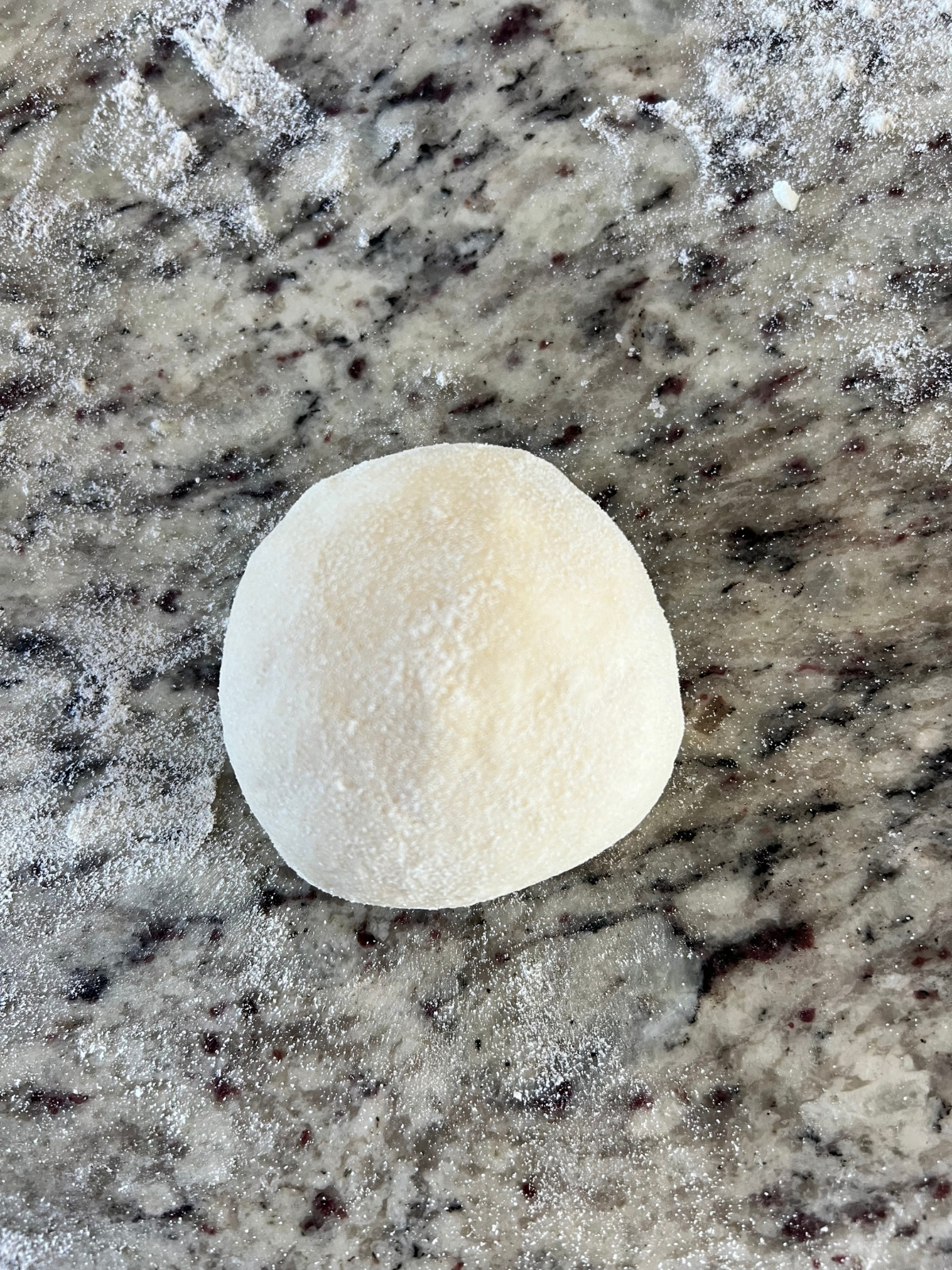 The sourdough naan cheese-stuffed dough ball has been rolled into a round ball. 
