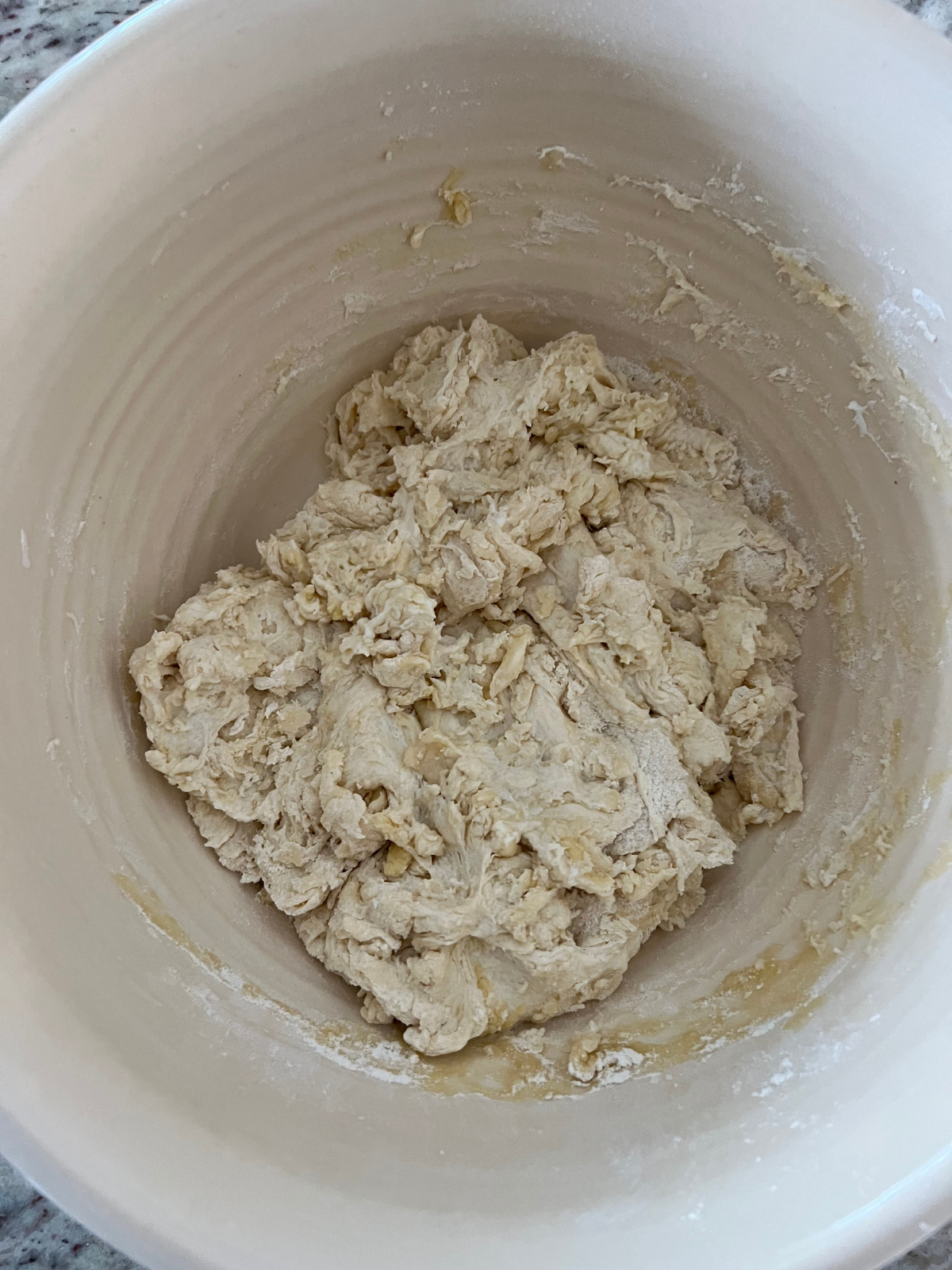 A mixing bowl holds the shaggy dough before it is kneaded.