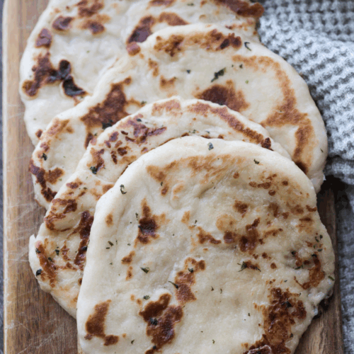 Four mozzarella cheese-stuffed garlic butter sourdough naan sits on a wooden serving board.
