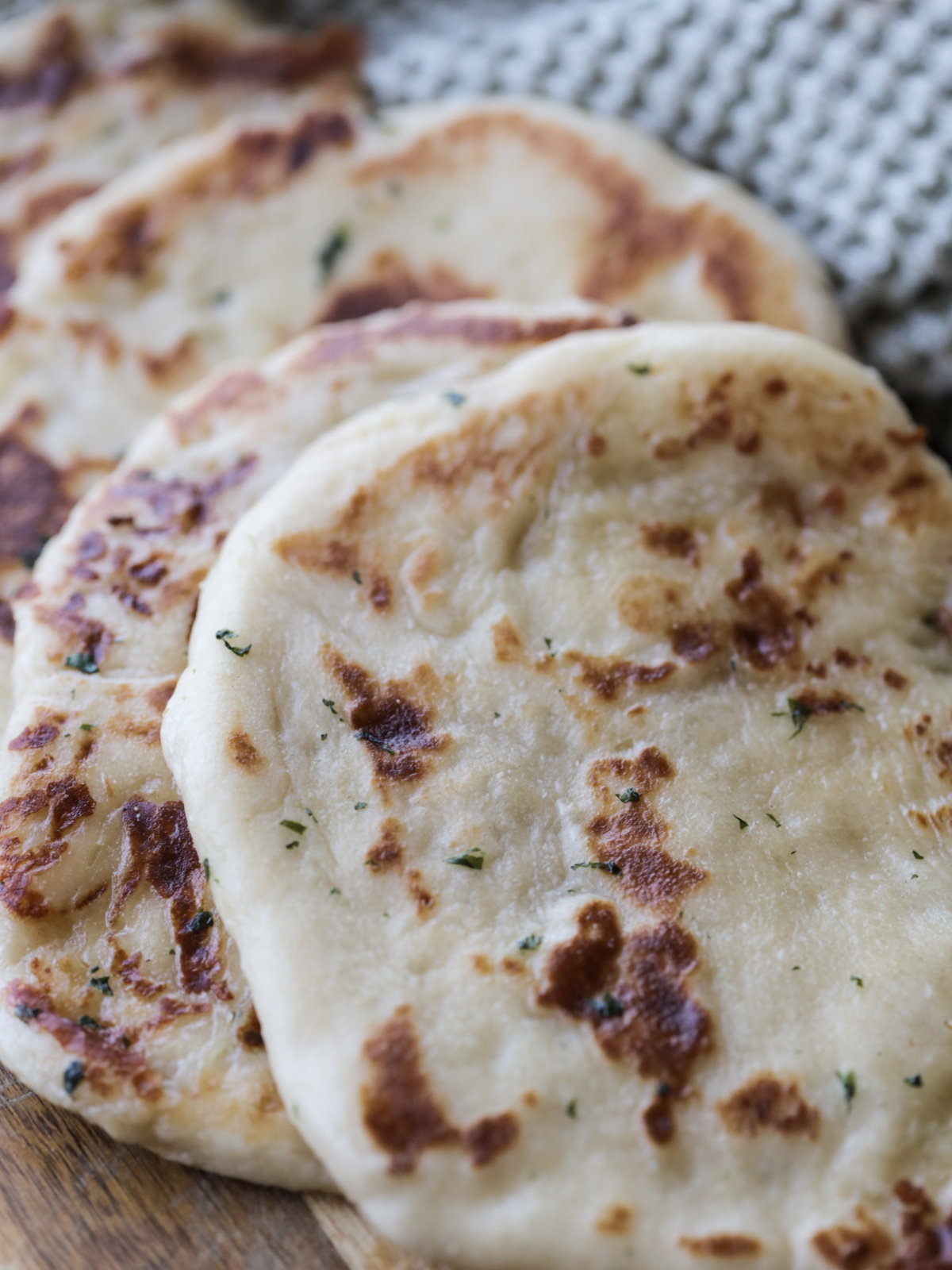 Several sourdough naan sit warm on a plate ready to be served with dinner.