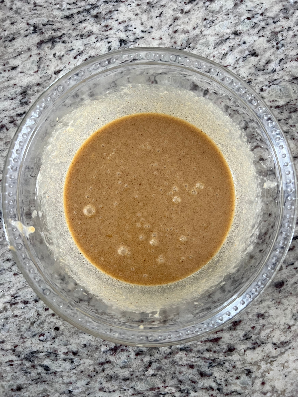 The wet ingredients for the sourdough skillet cookie sit in a glass mixing bowl.