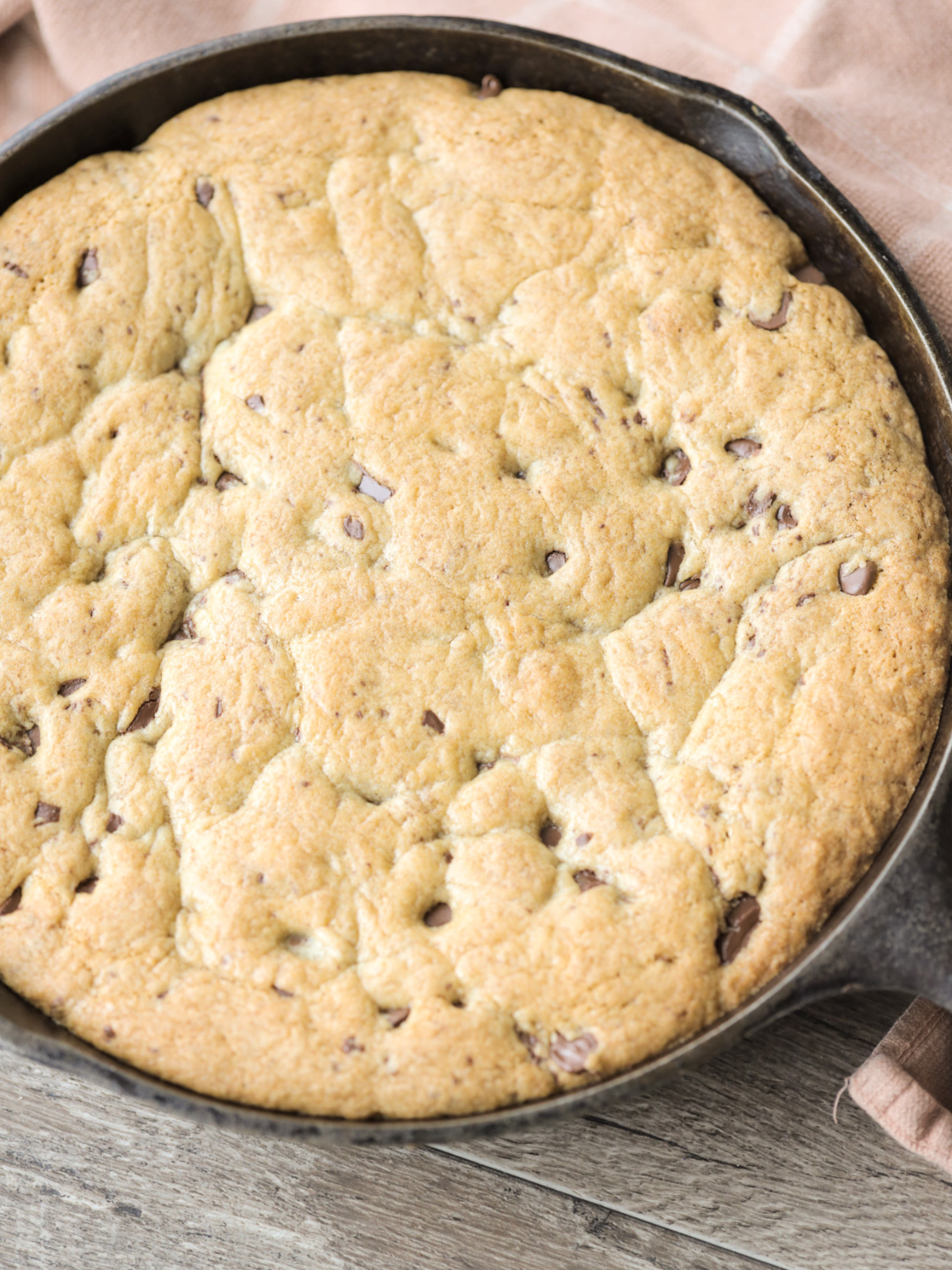 Freshly baked sourdough brown butter chocolate chip skillet cookie sits in a cast-iron skillet.