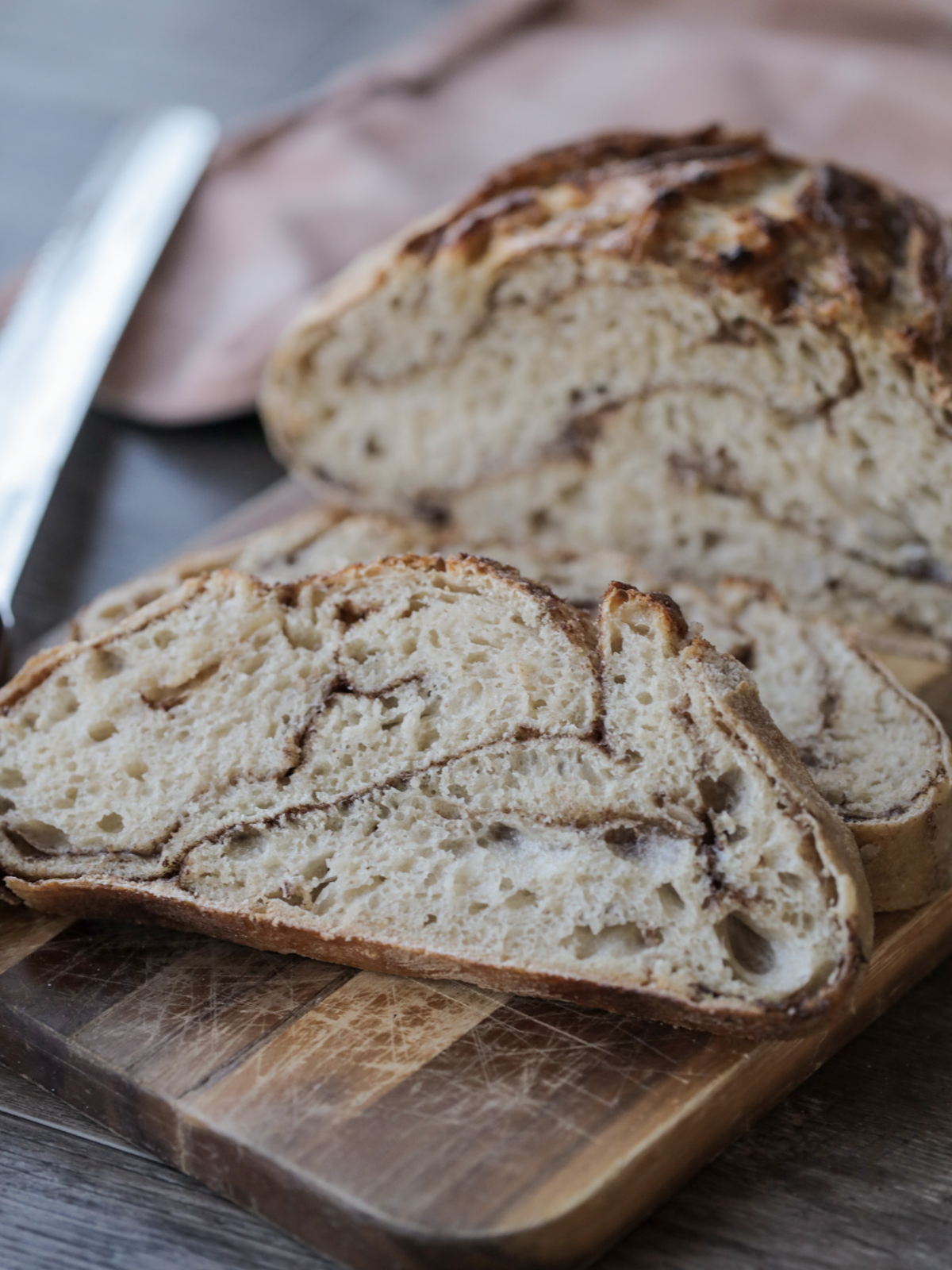 Several slices of sourdough cinnamon sugar bread sits on a wooden cutting board.
