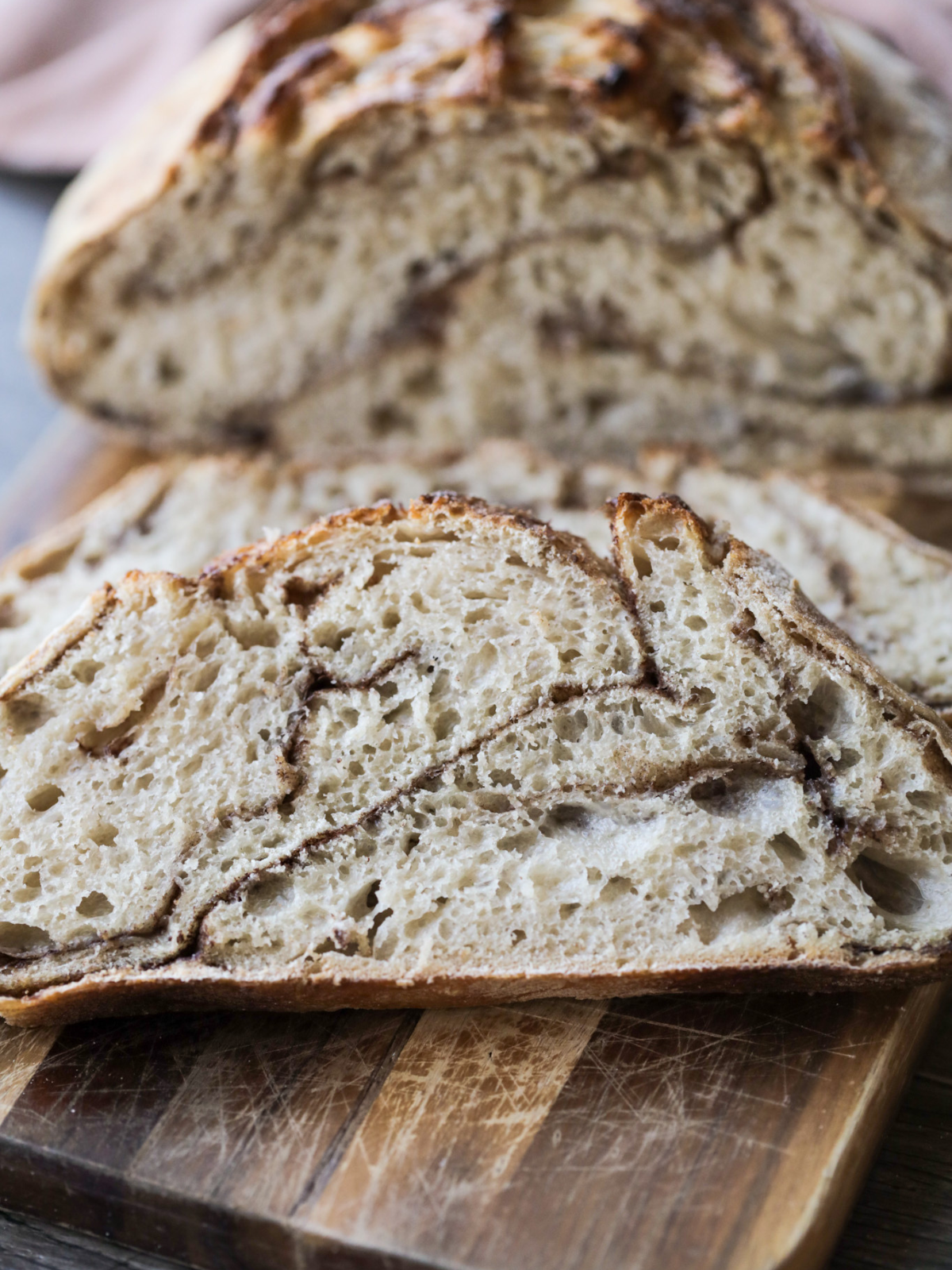A closeup of sourdough cinnamon sugar bread slices on a wooden cutting board.