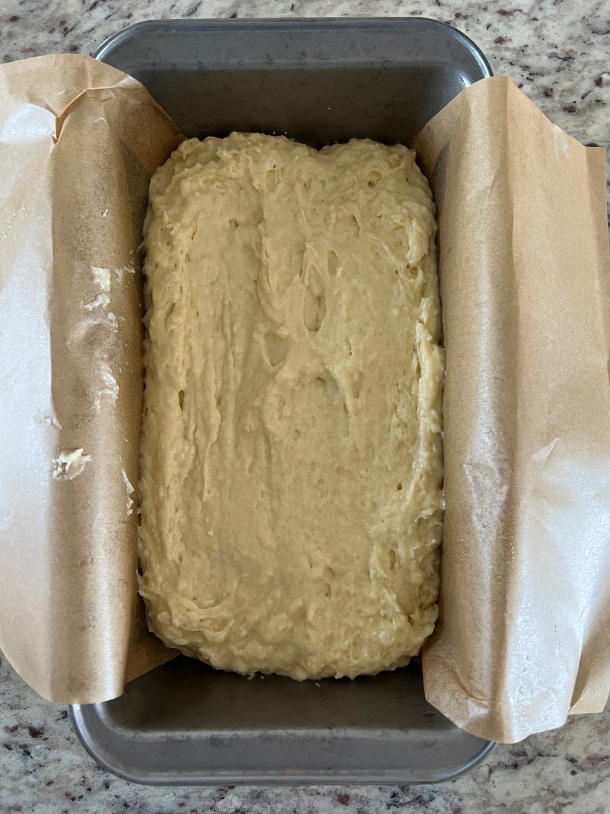 The sourdough discard lemon pound cake batter sits in the prepared loaf pan.
