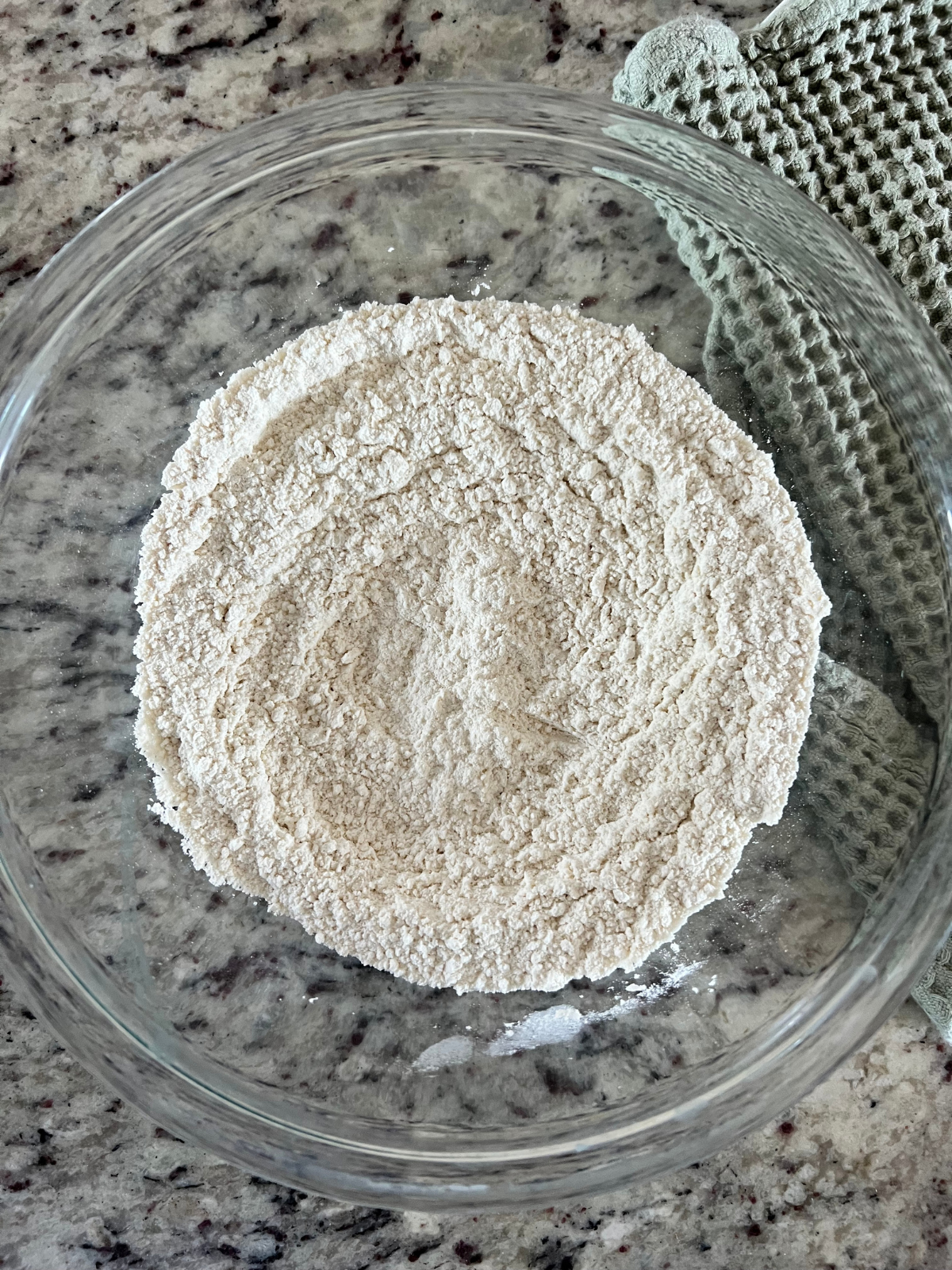 The dry ingredients sit in a glass mixing bowl preparing to be added to the wet ingredients for the sourdough discard lemon pound cake.