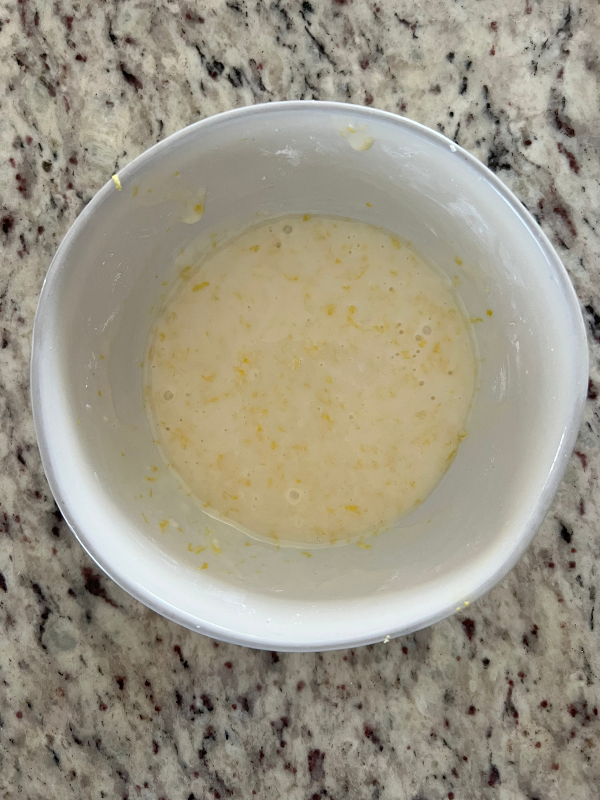 A bowl is shown containing the lemon glaze that will be poured over the pound cake.