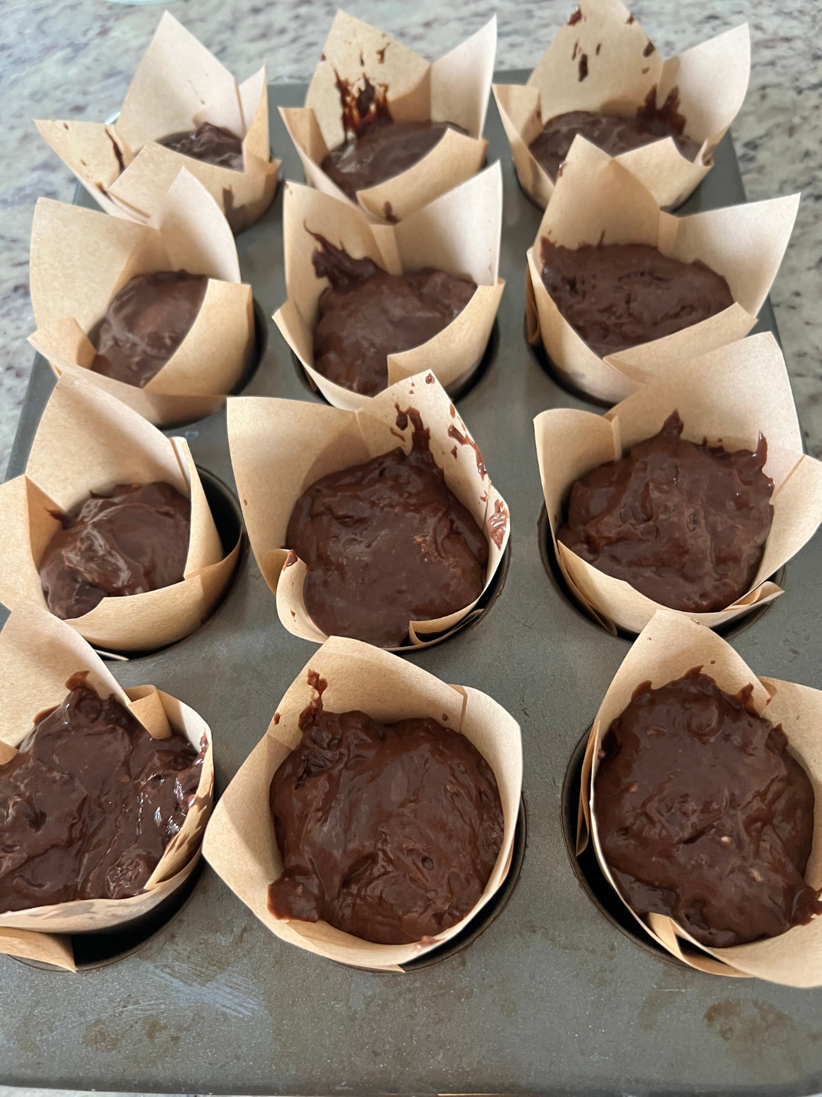 A muffin pan holds muffin batter in cupcake liners. 