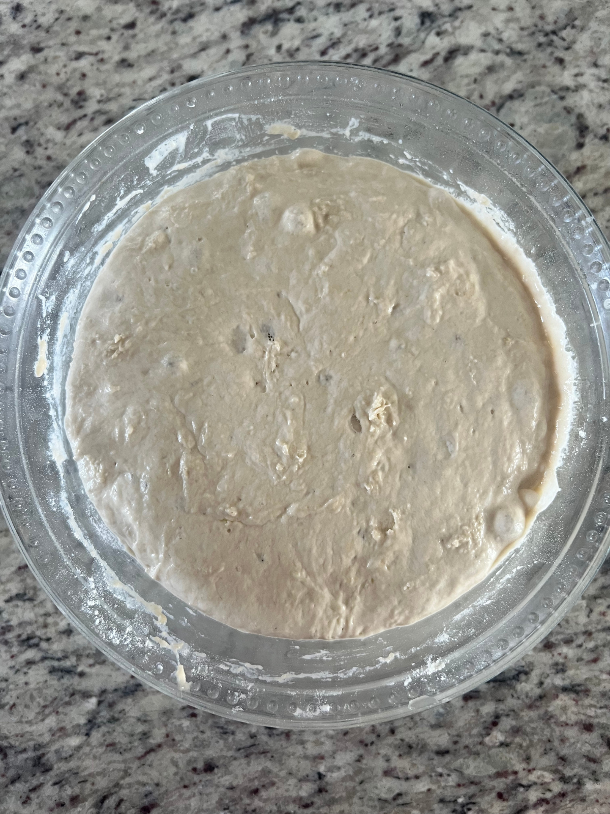 A glass mixing bowl contains the bulk fermented sourdough fry bread dough.