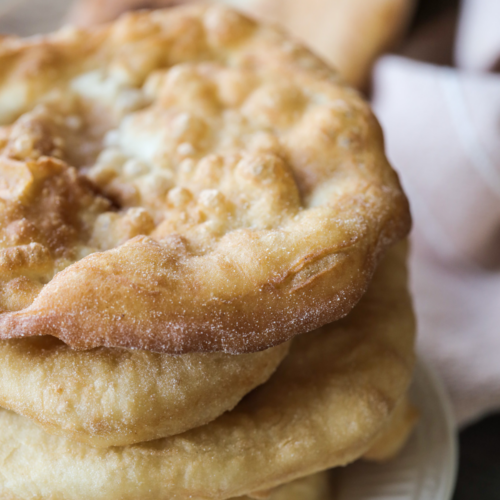 A stack of several sourdough fry bread sits on a plate.