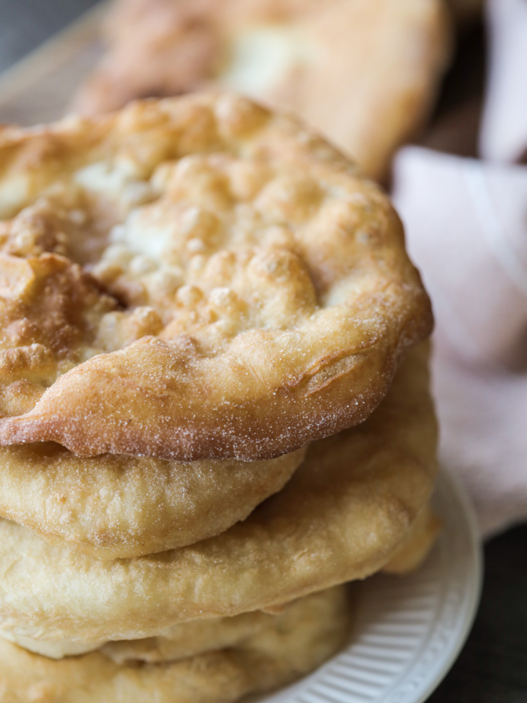 A stack of several sourdough fry bread sits on a plate.