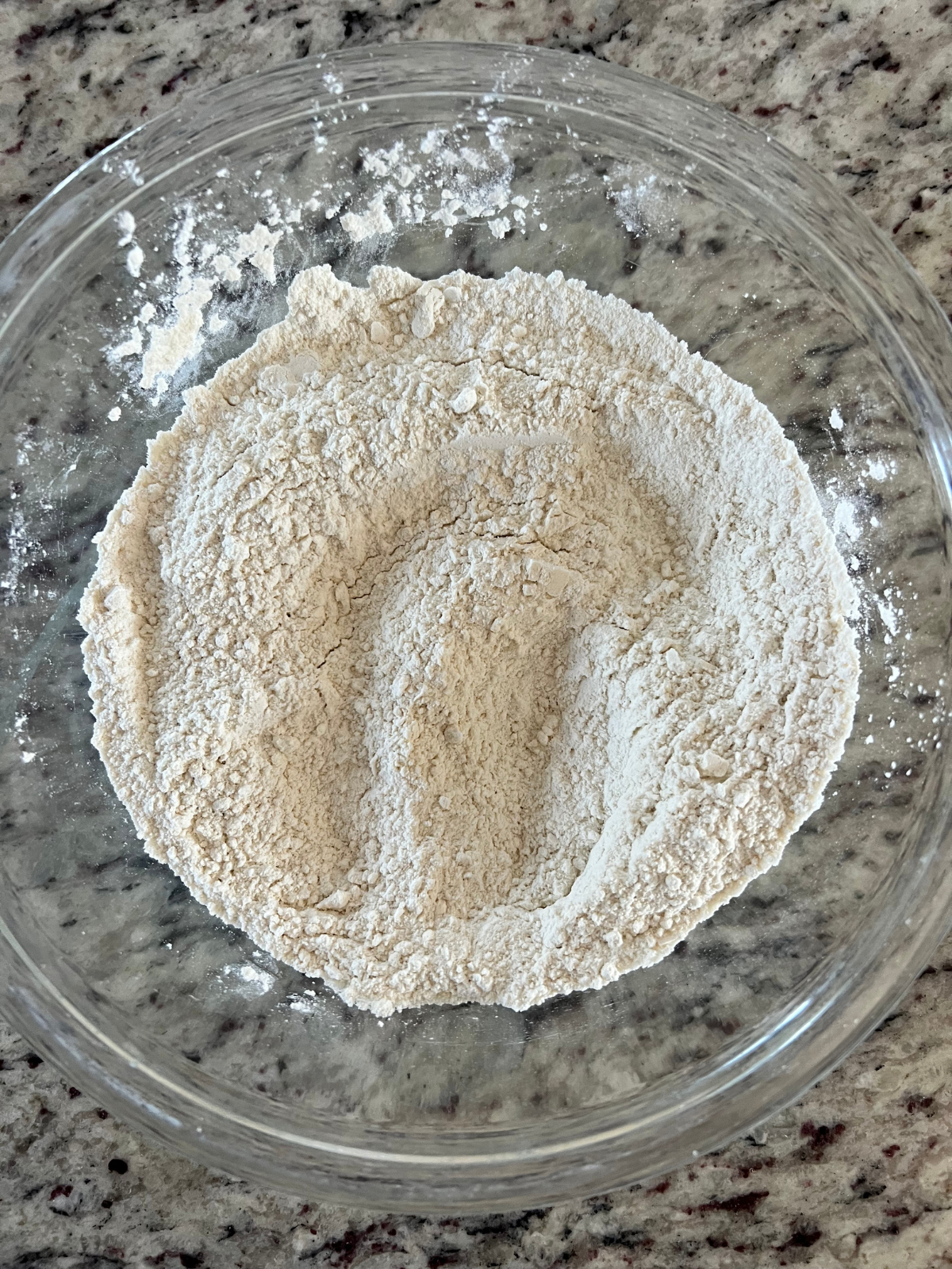 The dry ingredients for the sourdough discard lemon scones sit in a glass mixing bowl.