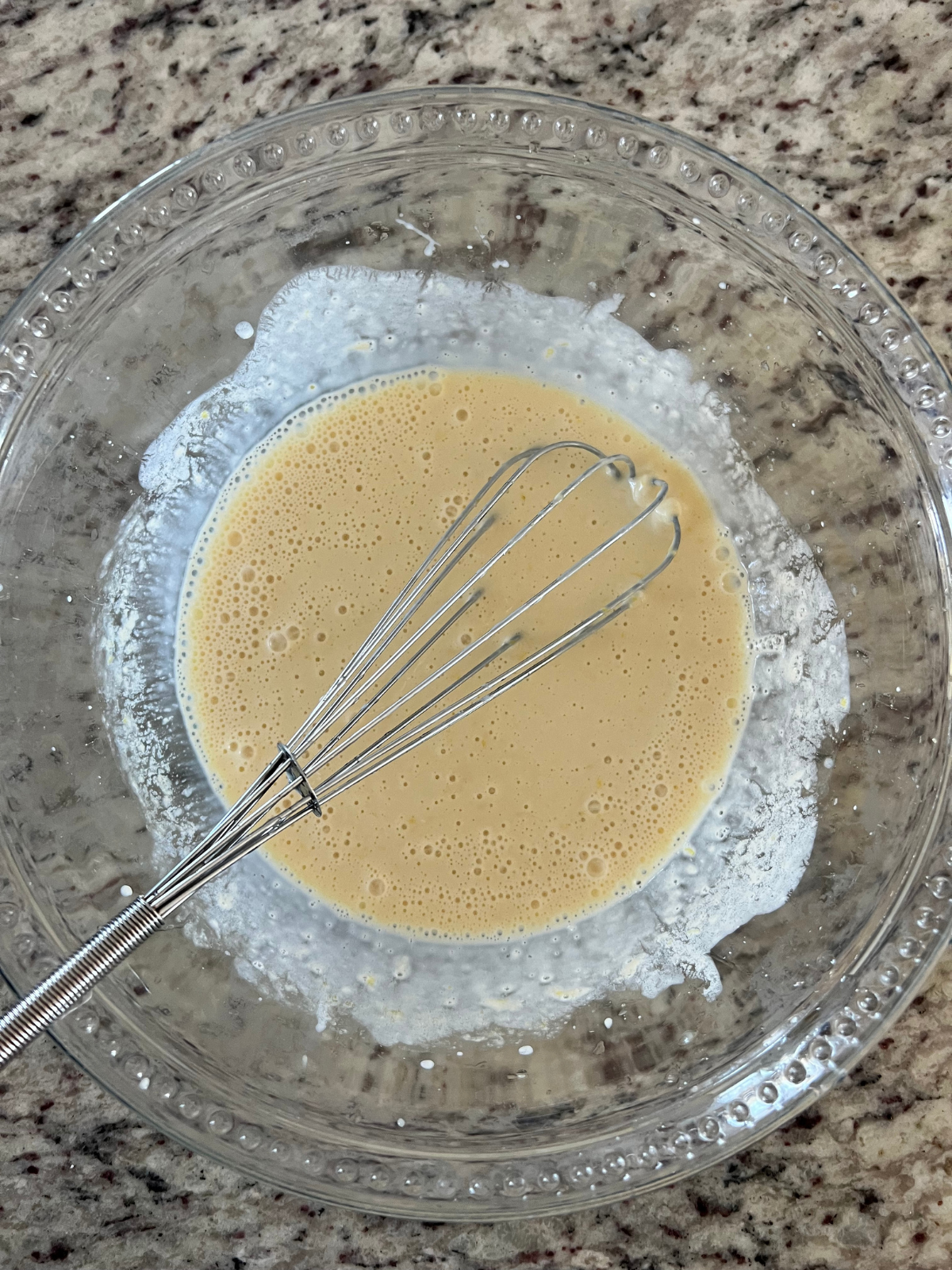 The wet ingredients are whisked together in a glass bowl ready to be poured into the dry ingredients for the lemon sourdough scones.
