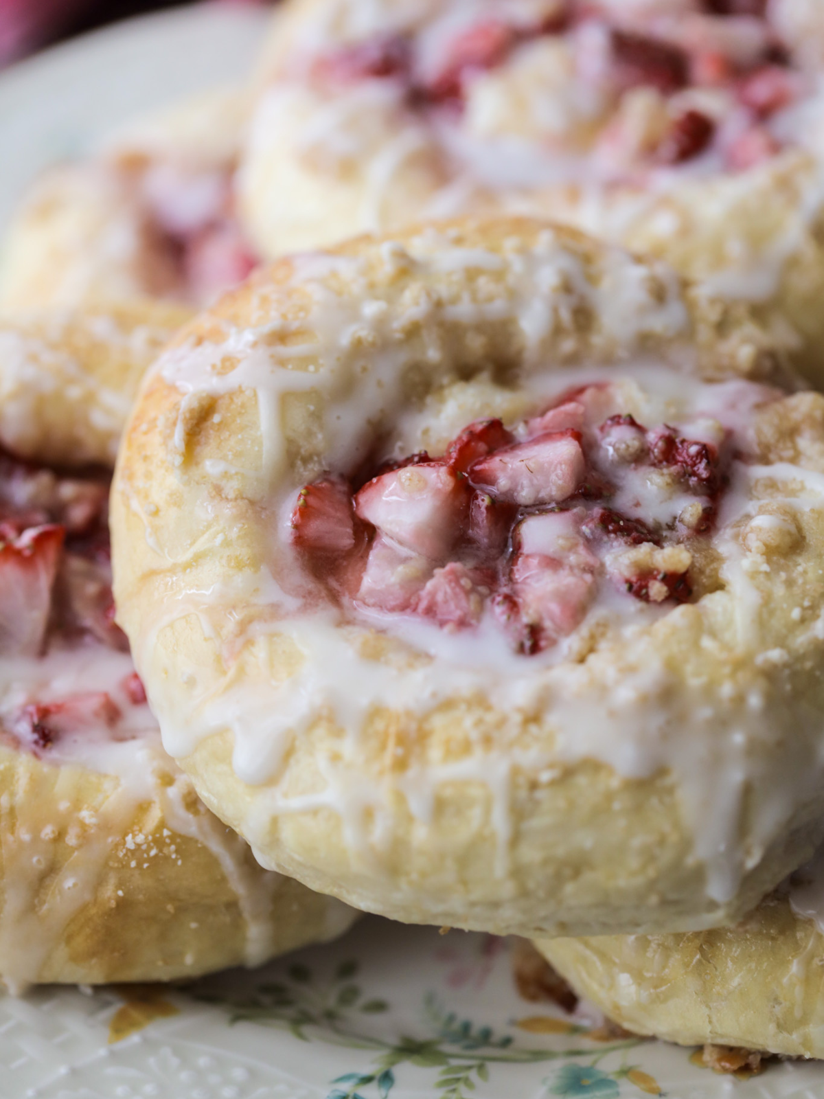 A closeup of a sourdough strawberry cream cheese bun with icing drizzled over it.