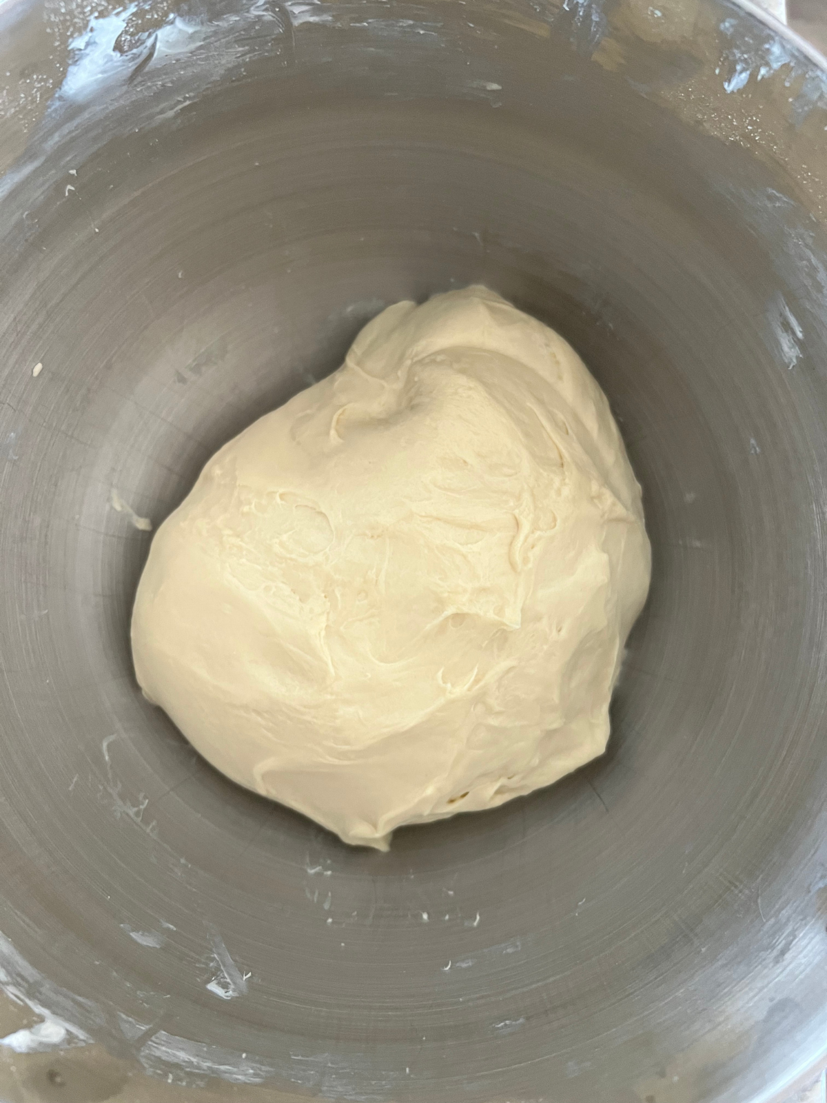 The sourdough brioche dough sits in the bowl of a stand mixer after being kneaded.