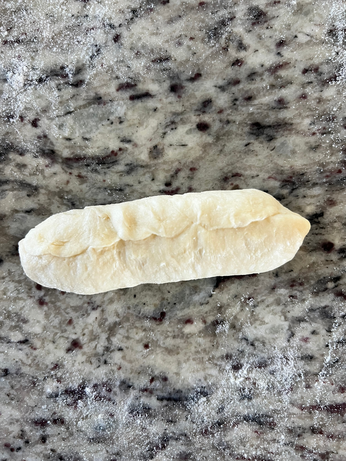The dough has now been rolled into a hot dog bun with the edges and seams pinched together.