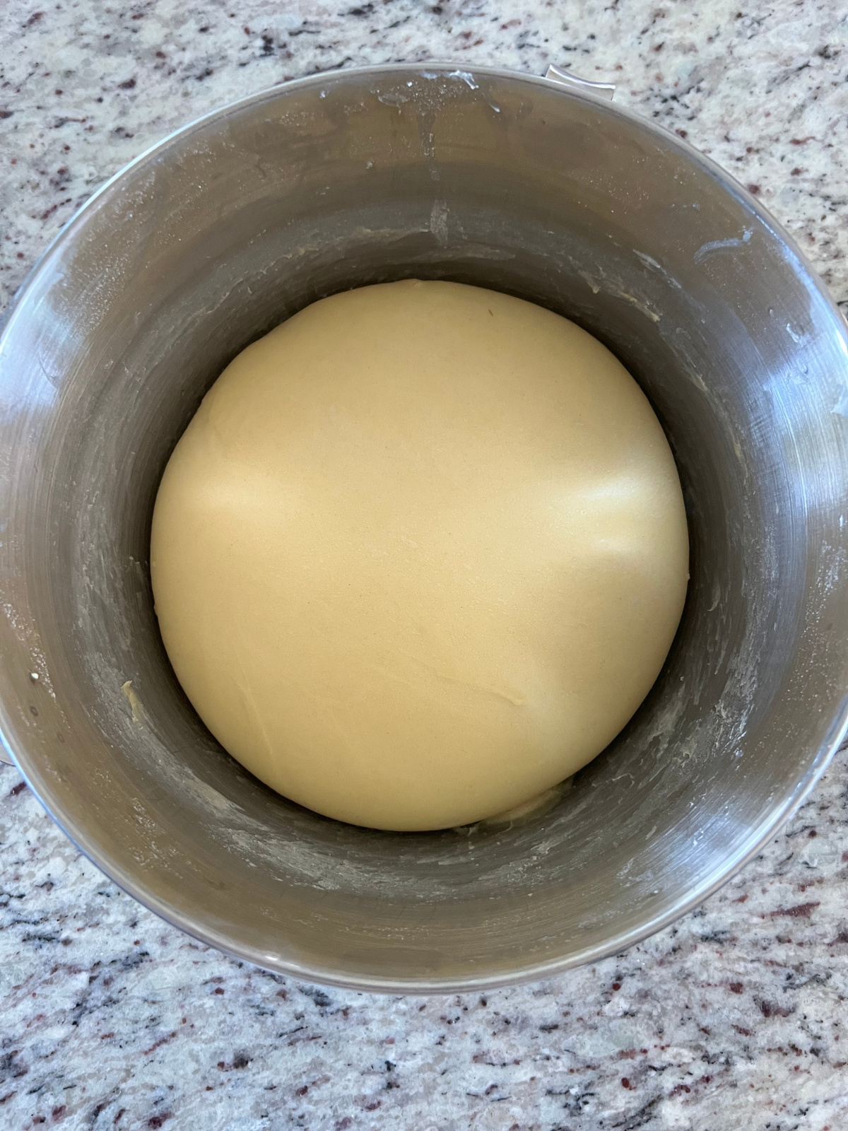 The sourdough hot dog bun dough is shown in the bowl after visibly rising. 