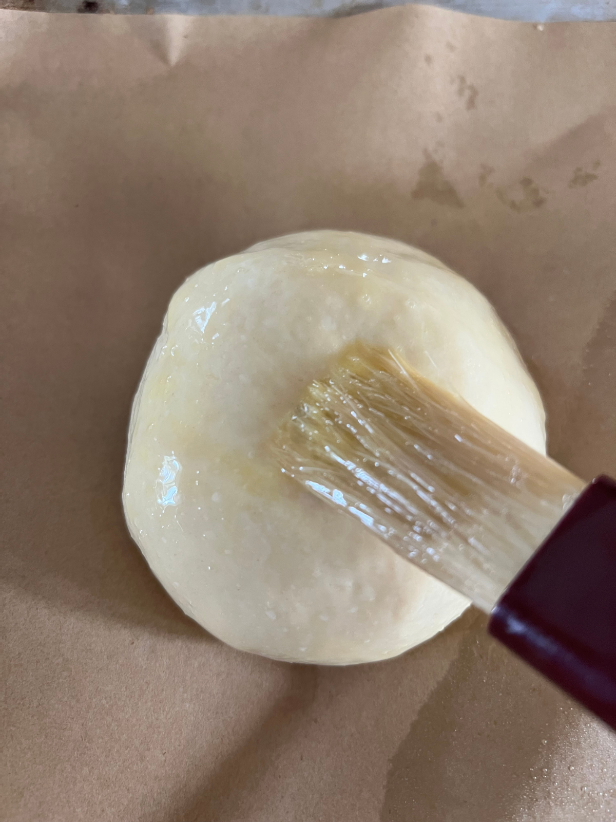 The egg wash is being brushed over one of the dough balls.