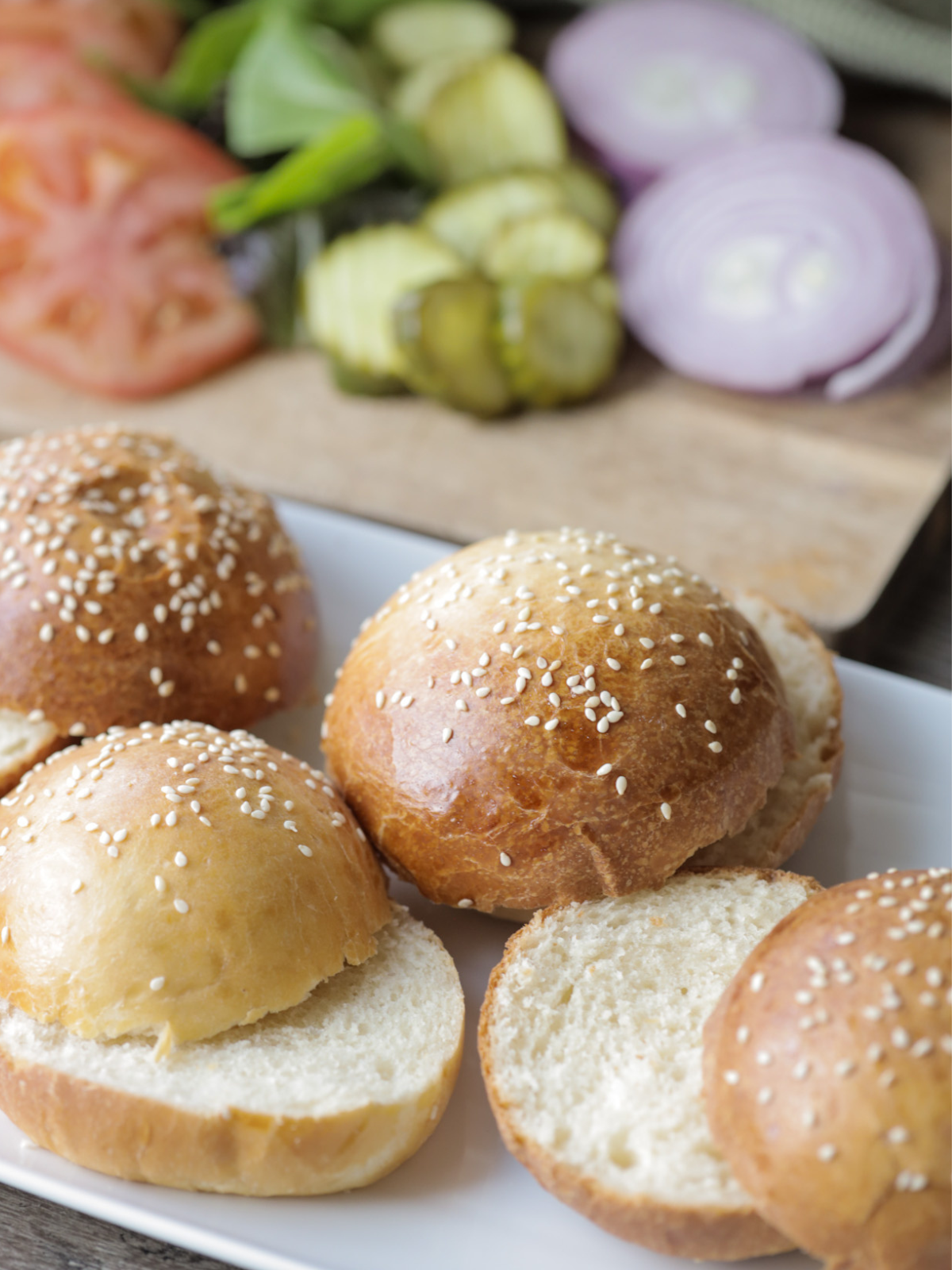 The best brioche sourdough burger buns are shown cut in half and resting on a platter.