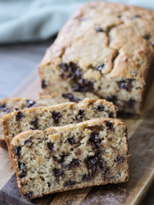 Three slices of sourdough chocolate chip banana bread with the rest of the loaf in the background.