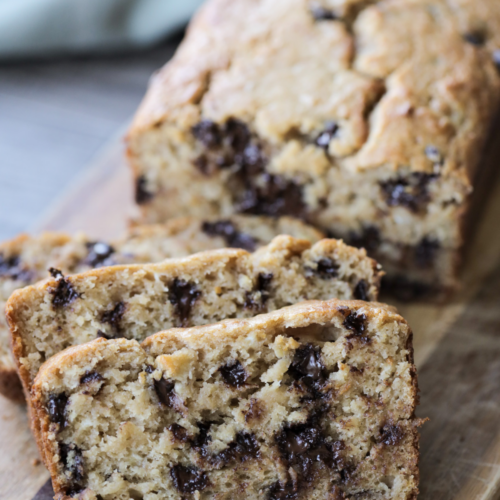 Three slices of sourdough chocolate chip banana bread with the rest of the loaf in the background.