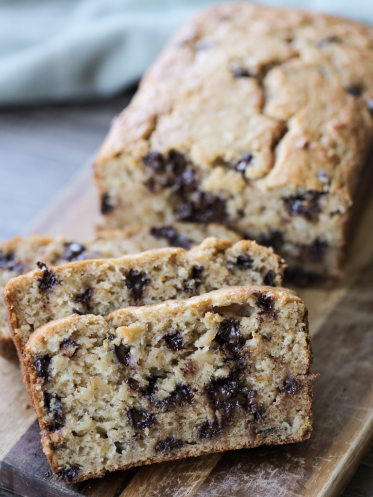Three slices of sourdough chocolate chip banana bread with the rest of the loaf in the background.