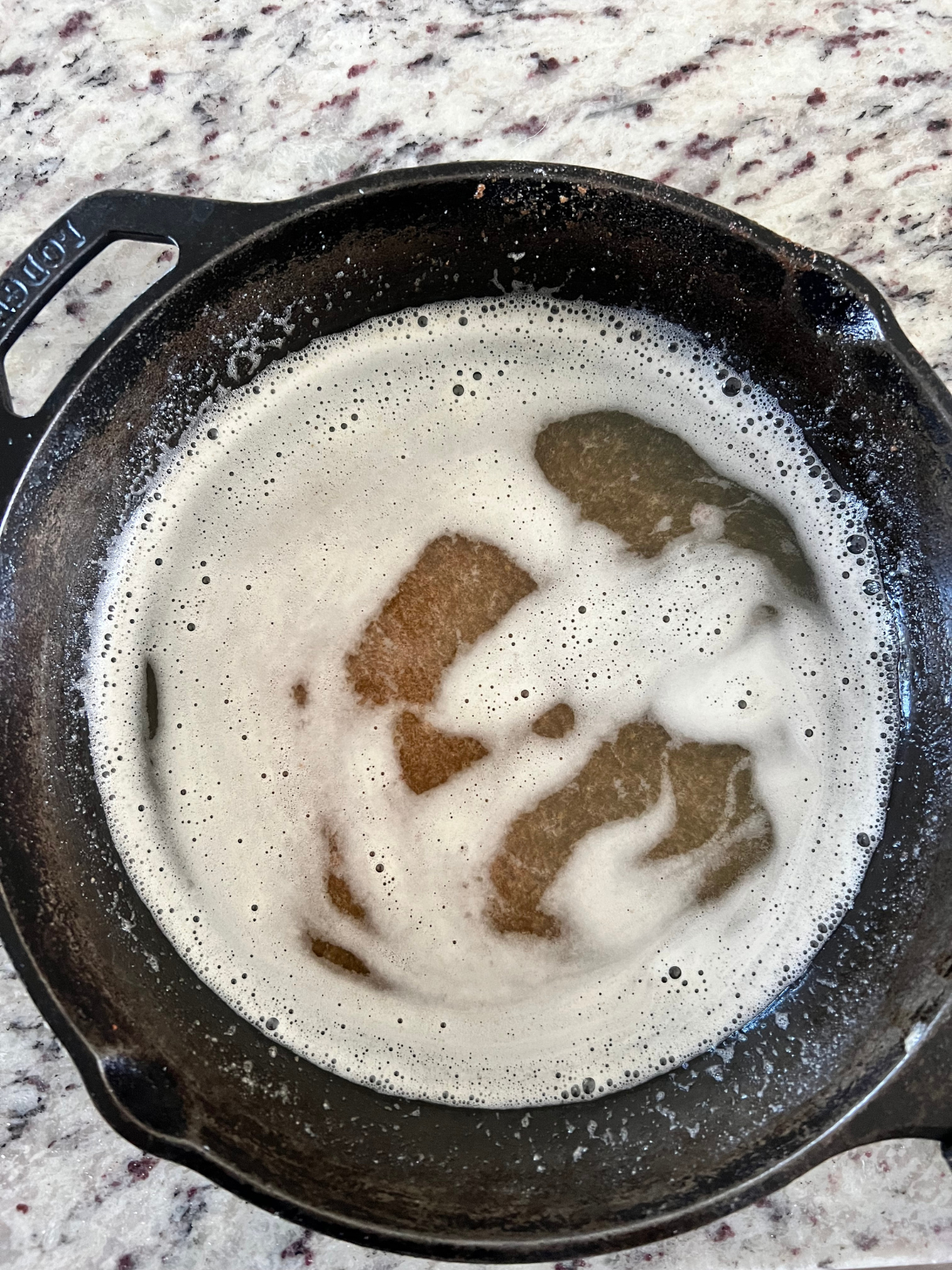 Browned butter sits in a cast-iron skillet ready to pour into the sourdough banana bread batter.