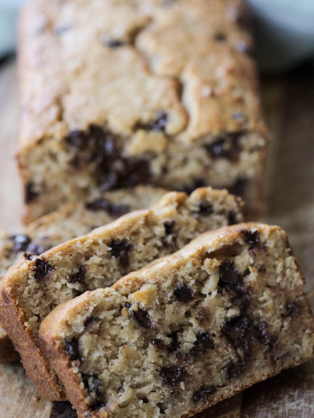 A closeup of the three slices of brown butter sourdough banana bread is shown with the loaf in the background. 