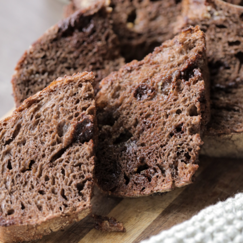 Several slices of sourdough chocolate coffee bread sit on a wooden cutting board.
