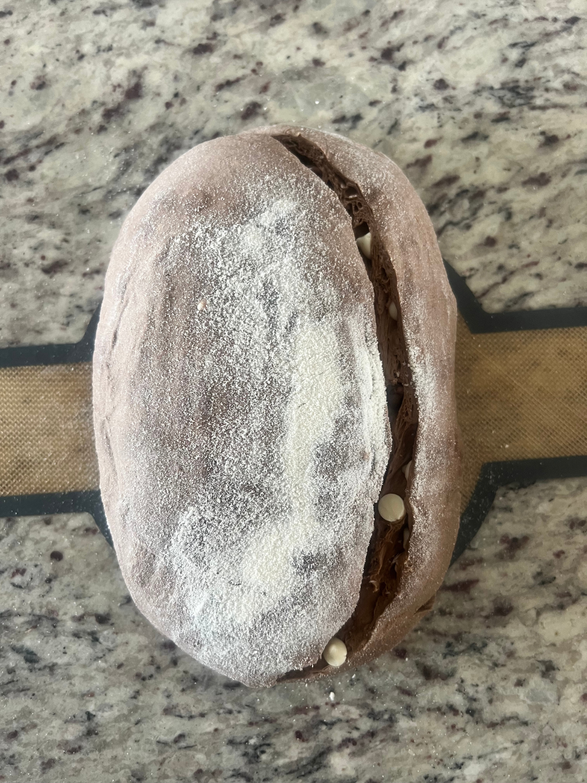 The sourdough chocolate and coffee dough is shown scored after its overnight cold ferment. It rests on a bread sling.