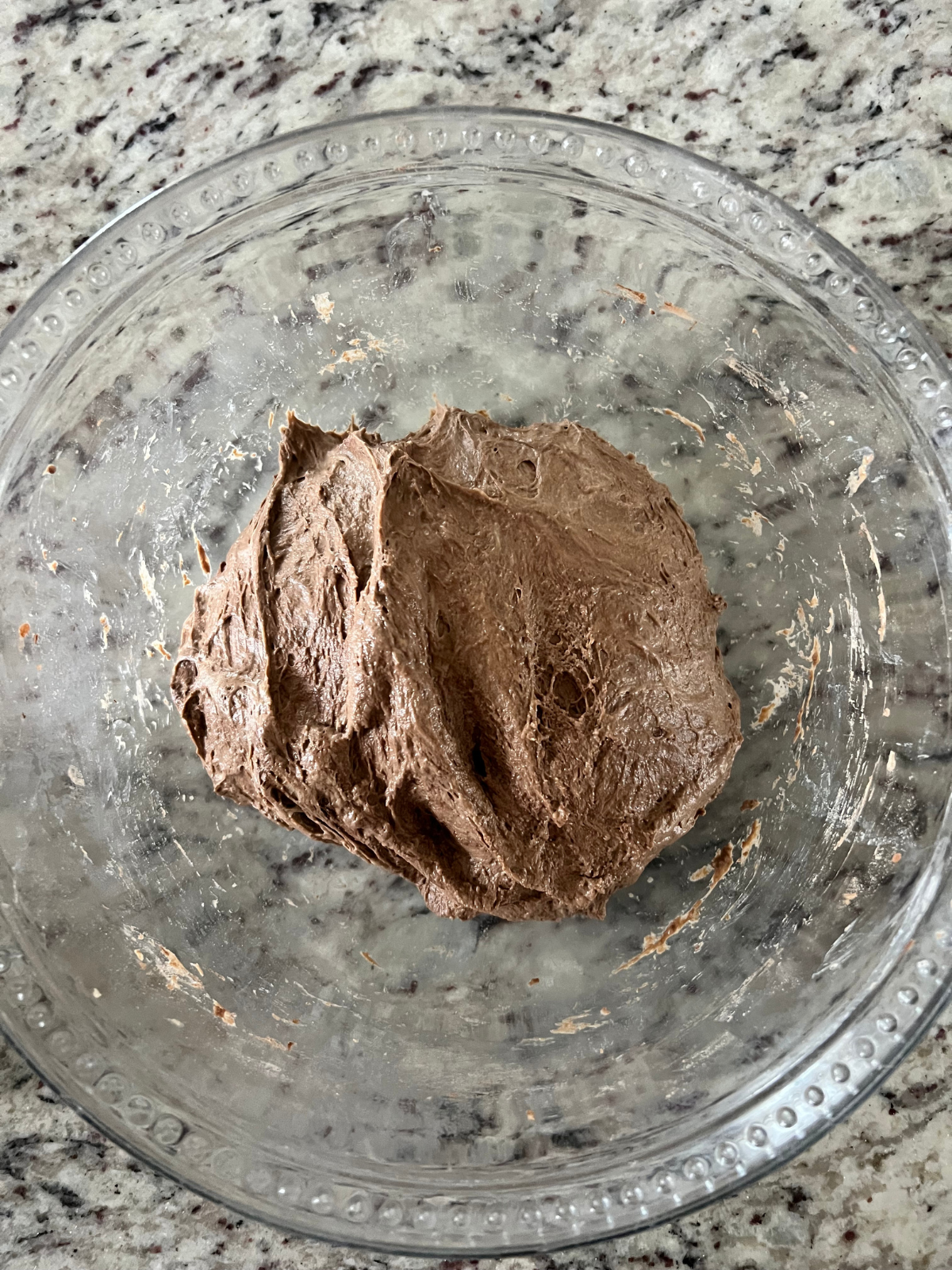 Sourdough chocolate coffee bread dough sits in the glass mixing bowl after adding the salt to it.