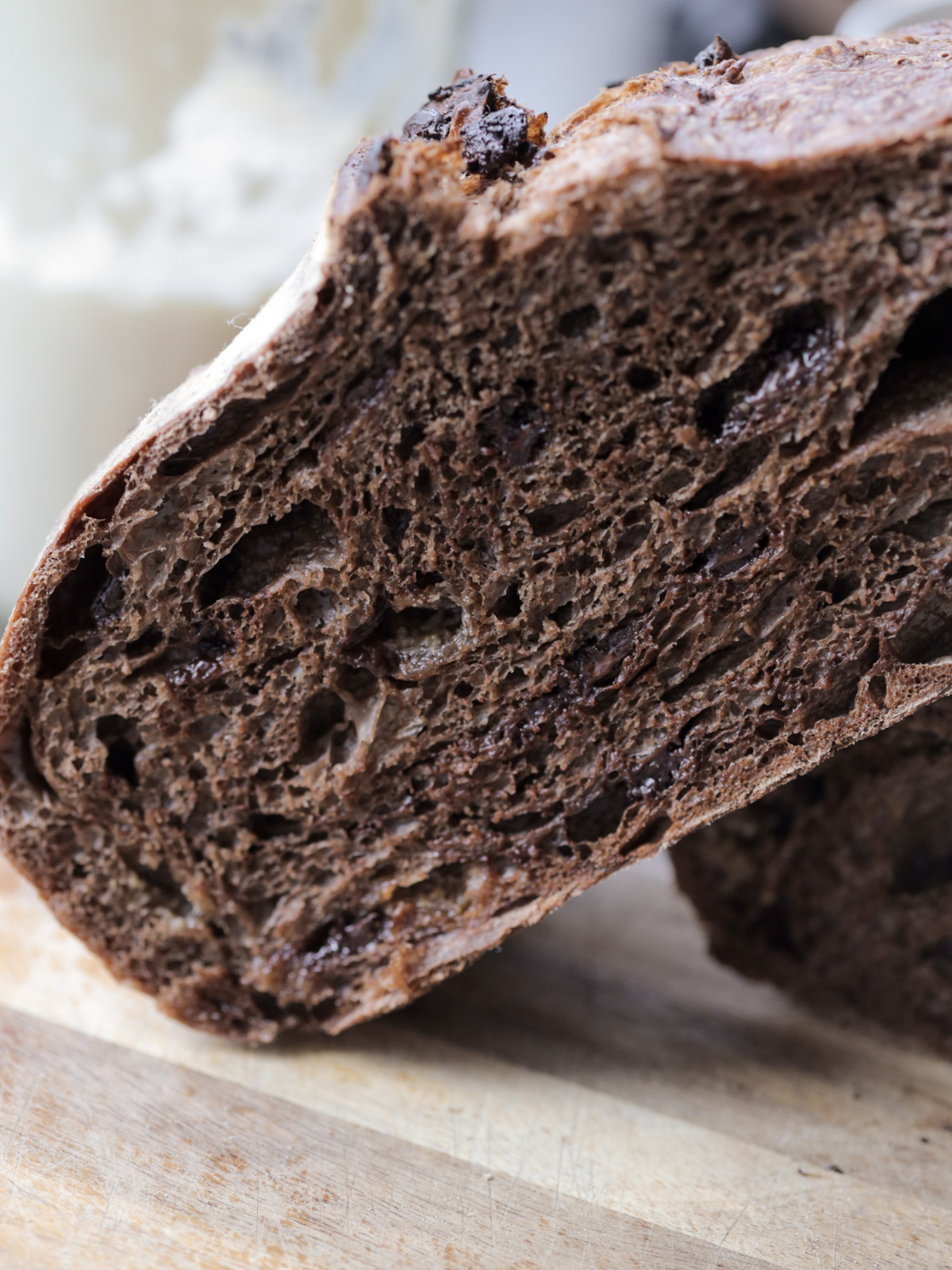 Half of a sourdough chocolate coffee bread rests on the other half of the loaf.