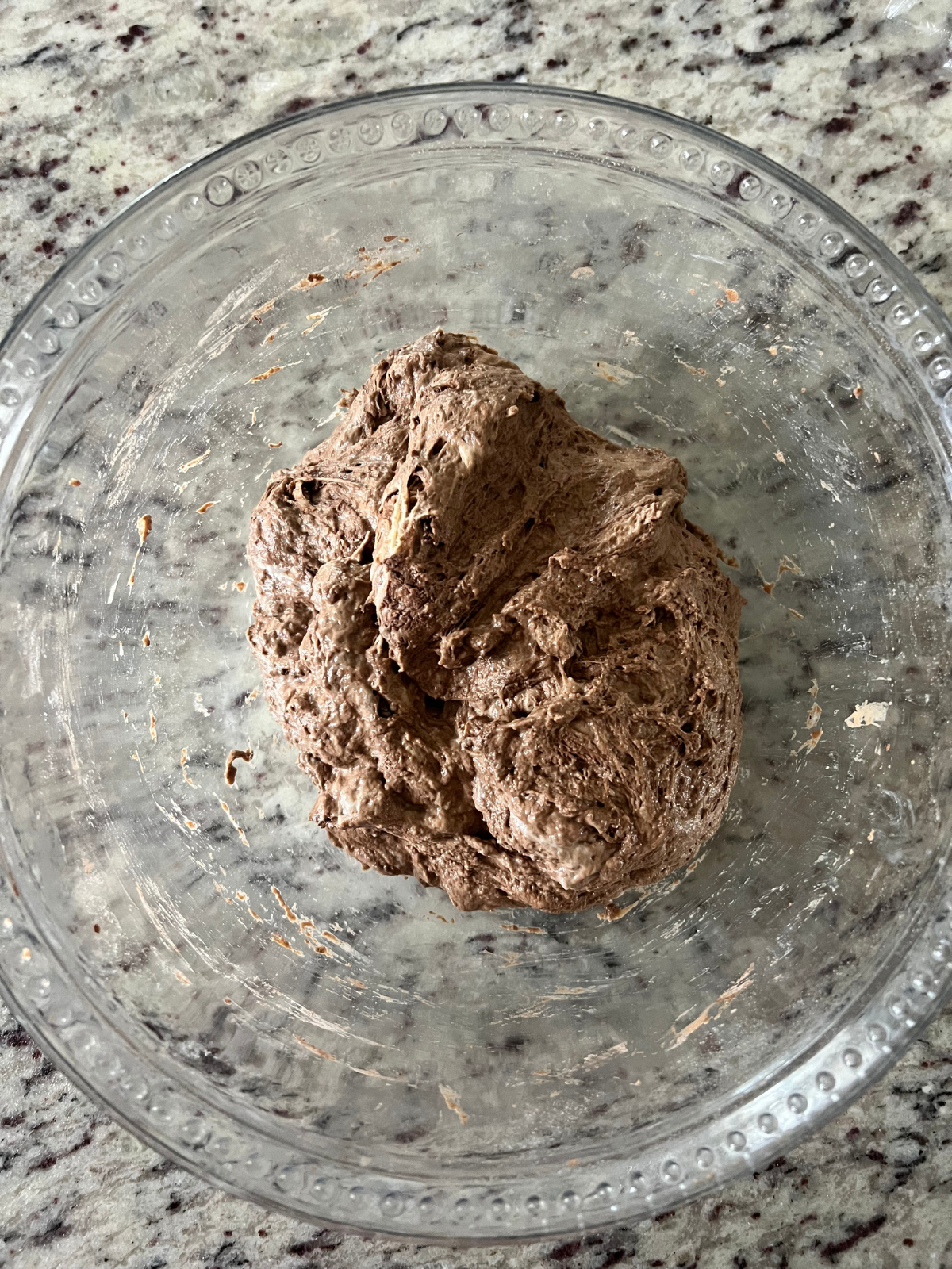 The sourdough chocolate coffee dough is shown in a shaggy ball in a glass mixing bowl.