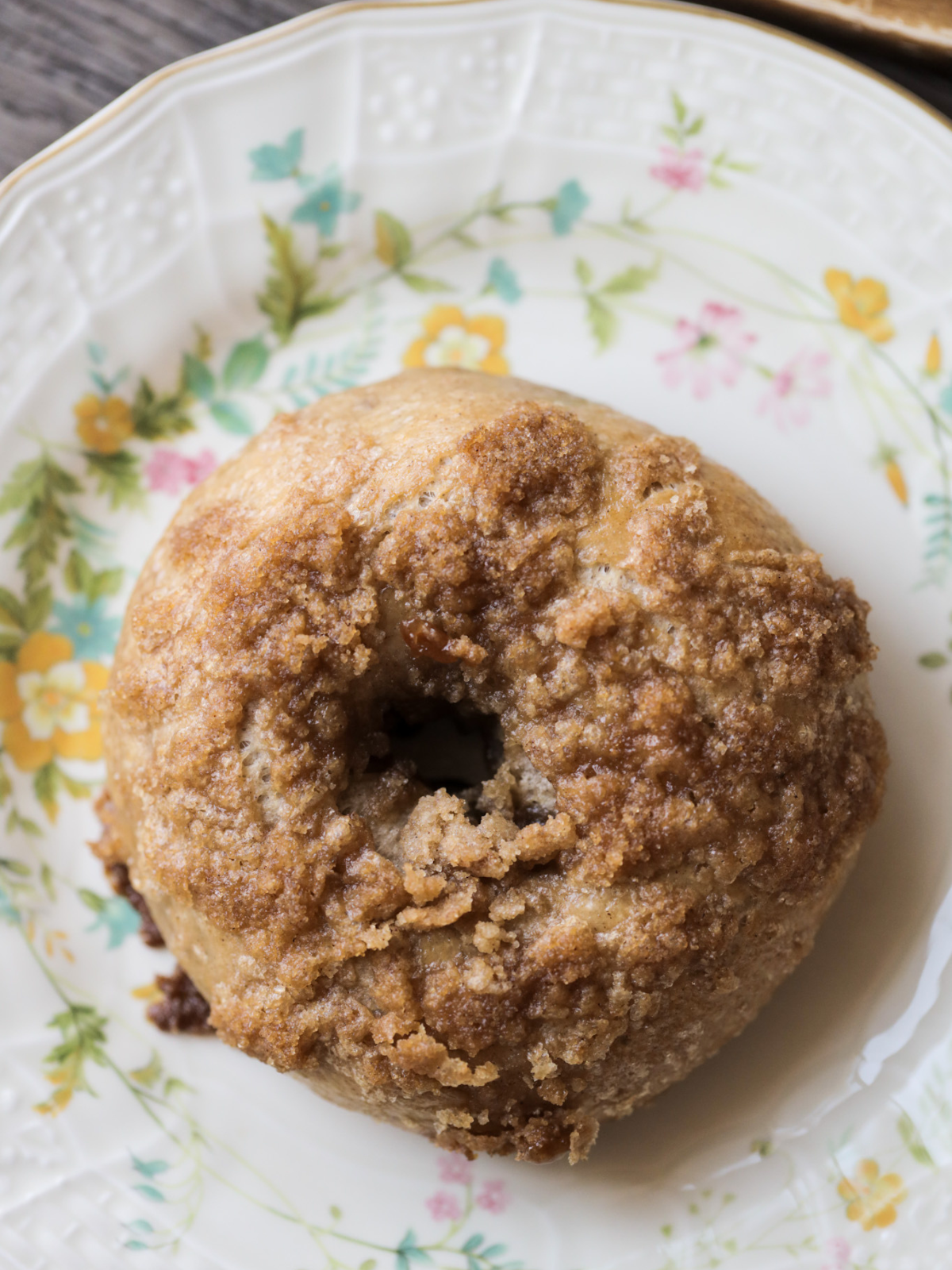 A sourdough cinnamon crunch bagel sits on a floral plate.