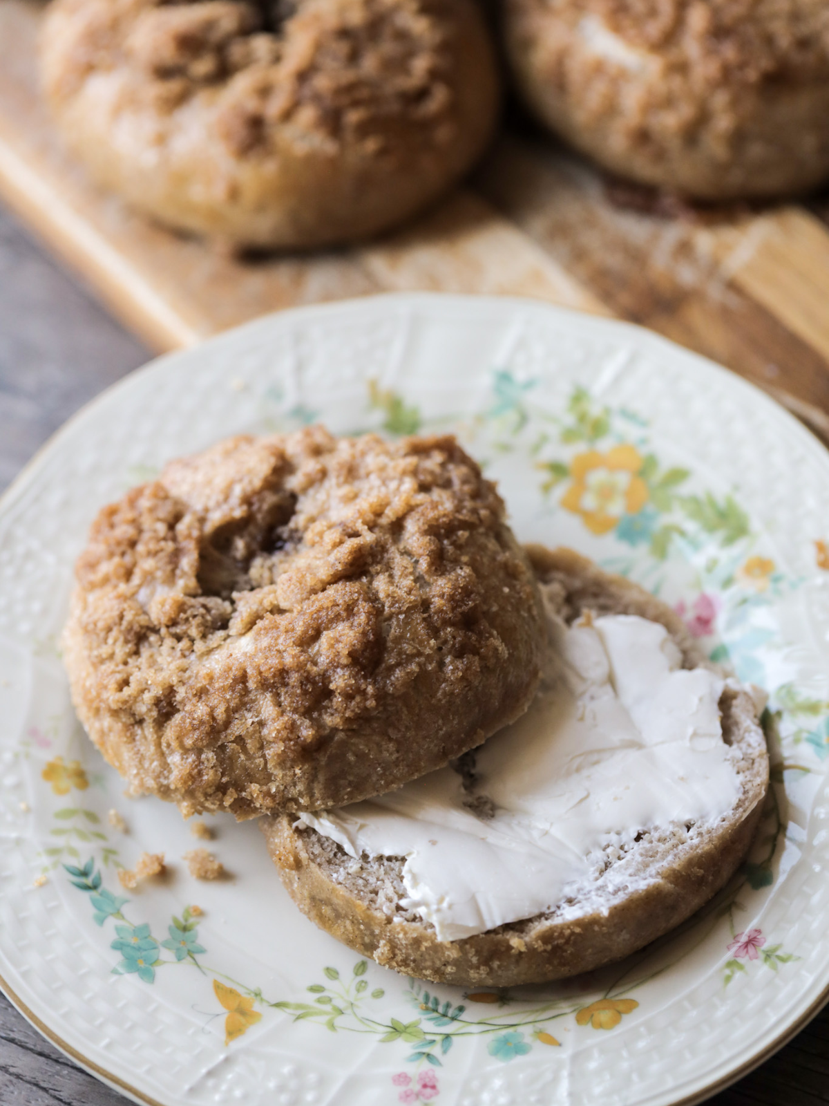 Sourdough cinnamon crunch bagels  in the background and one cut in half with cream cheese. 