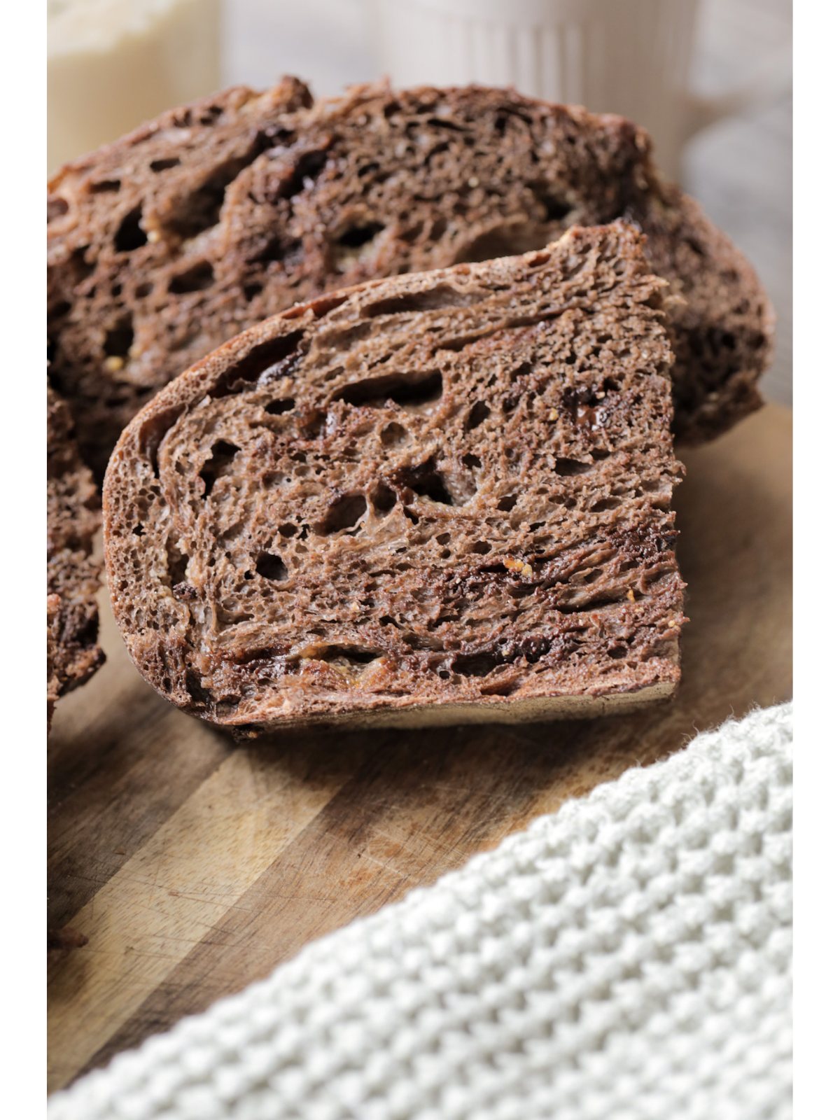 Half slices of sourdough chocolate coffee bread sit on a wooden cutting board.