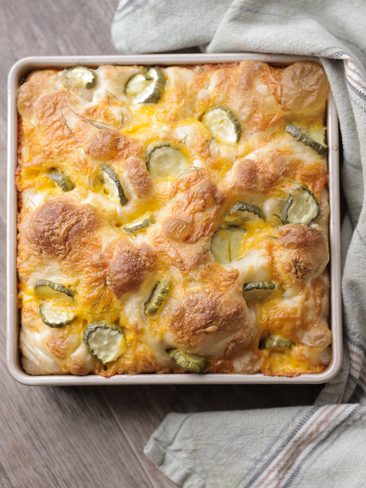 The pan of sourdough pickle focaccia sits after just coming out of the oven. 