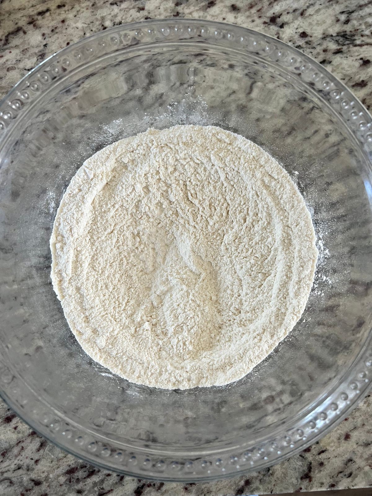 The dry ingredients for the strawberry sourdough coffee cake are shown in a glass bowl.