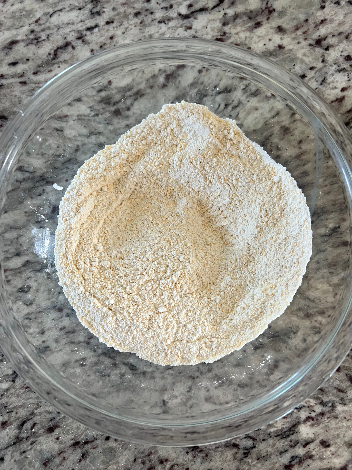 The dry ingredients for the sourdough brown butter cornbread cookies with honey buttercream frosting sits in a glass mixing bowl.