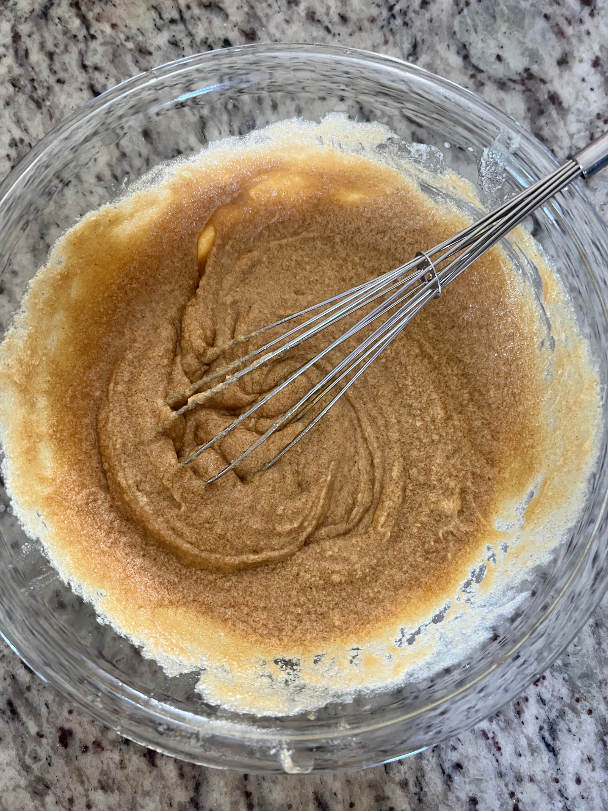 The wet ingredients for the sourdough honey buttercream cornbread cookies sit in a mixing bowl with a whisk in it.