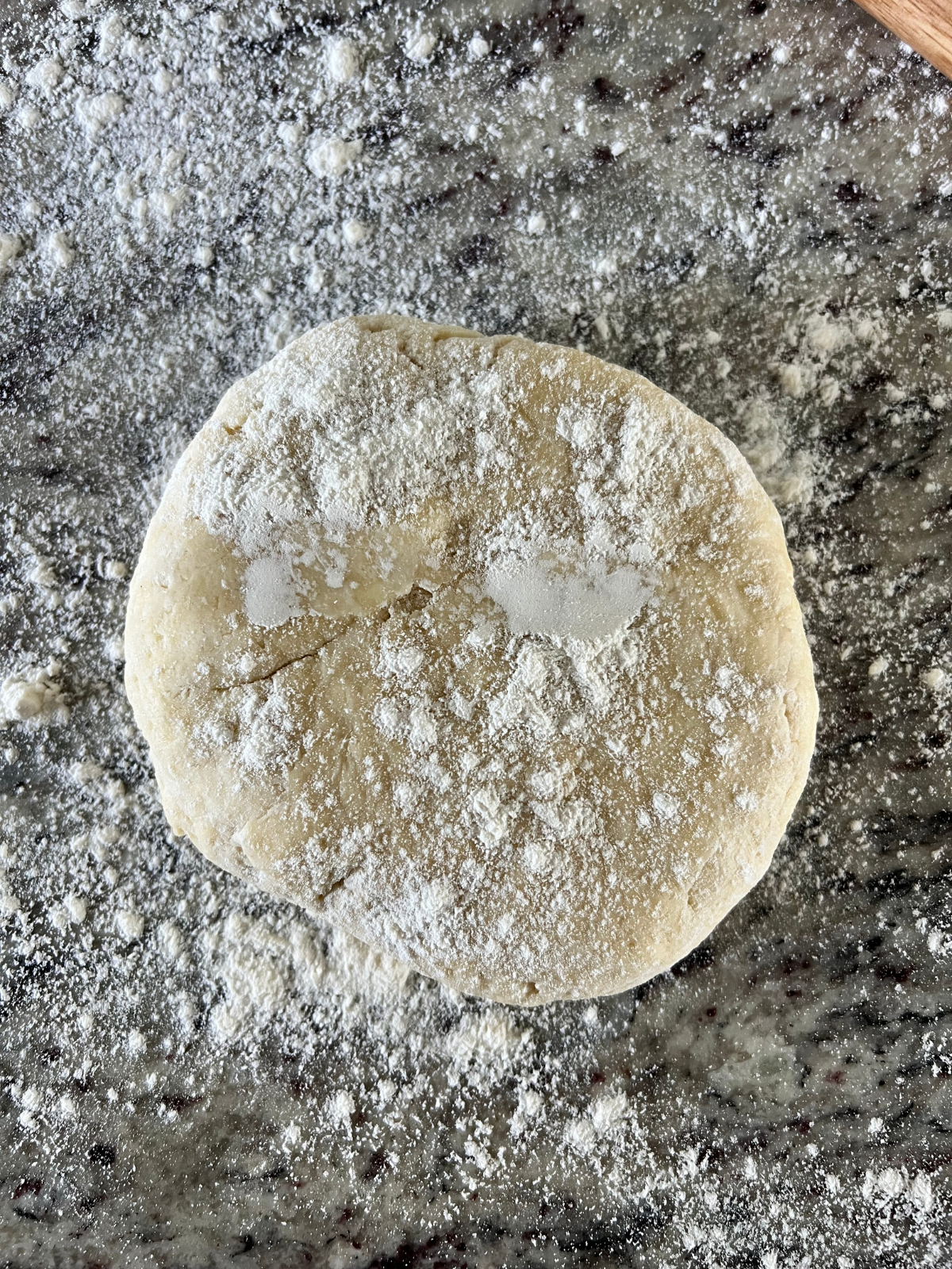 The sourdough discard hand pie dough is shown in a disc with flour sprinkled over it.