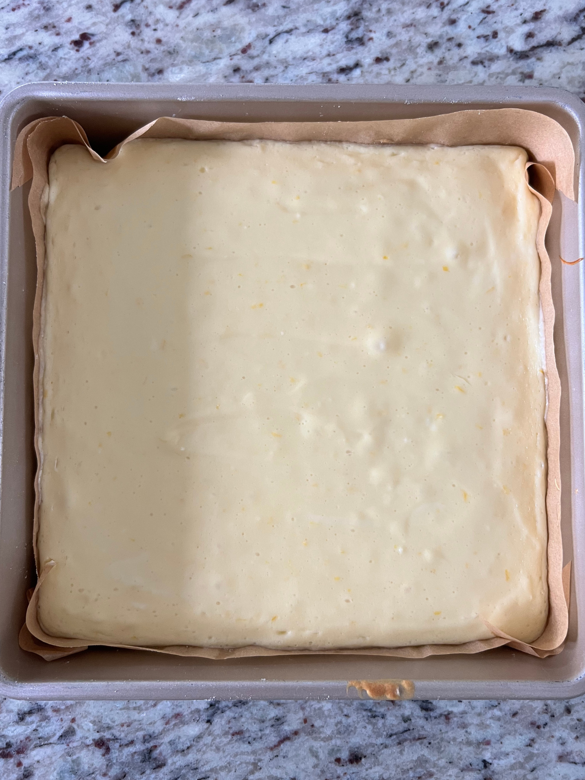 The slightly cooled lemon curd cheesecake sits on the counter. It will be transferred to the fridge overnight to chill.