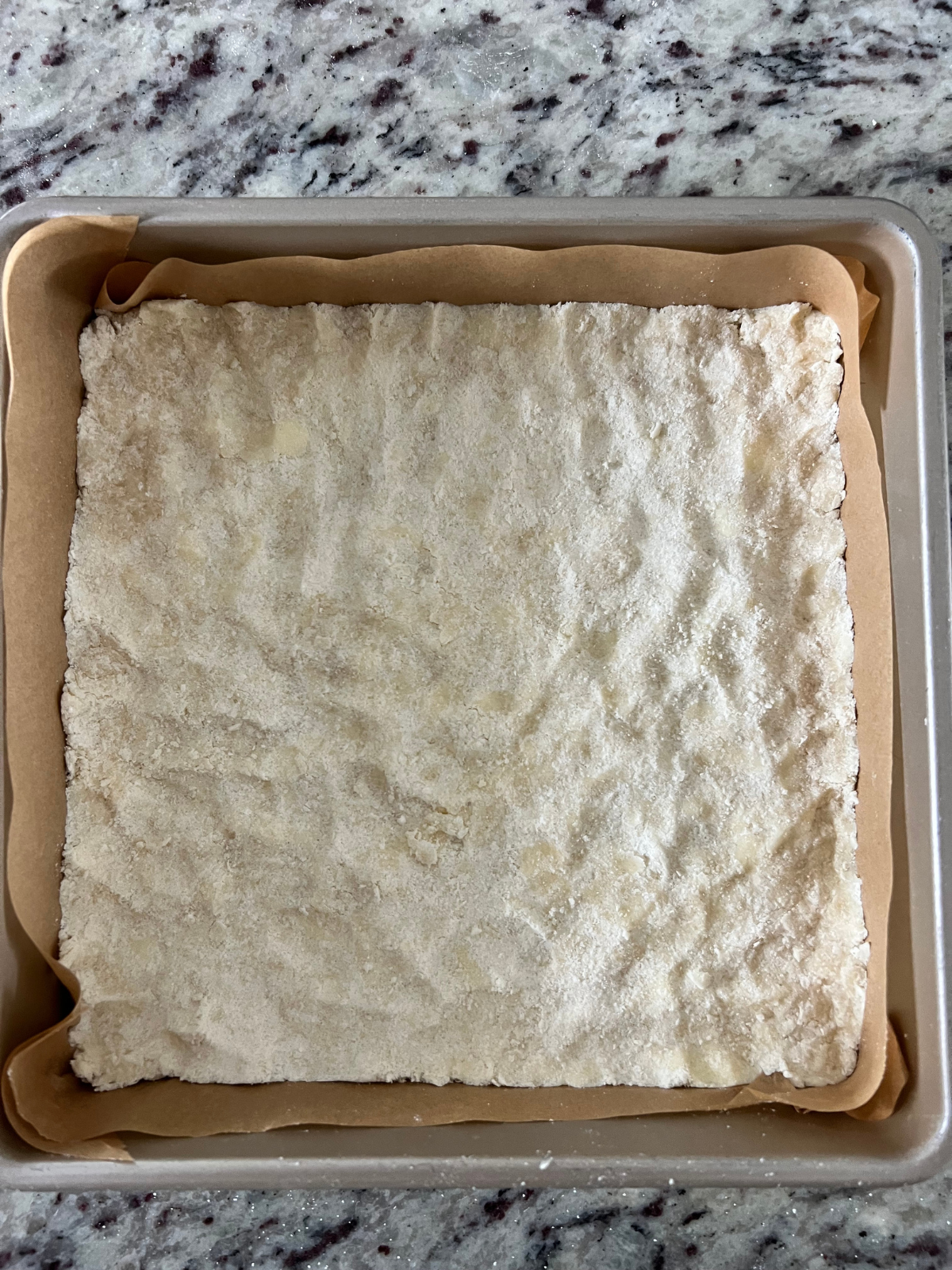 The sourdough shortbread crust has been pressed into the bottom of the parchment-lined 9x9 baking pan.