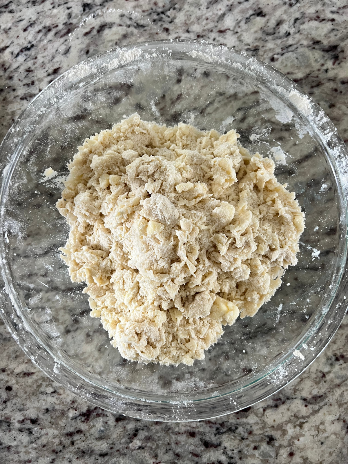 The crumbly sourdough shortbread crust sits in a glass bowl ready to be pressed into the baking pan.