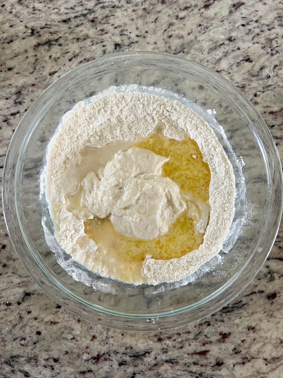 All of the ingredients for the sourdough discard tortillas are shown in a glass mixing bowl.