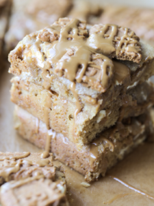 Three sourdough discard brown butter Biscoff blondies are shown stacked with a drizzle of Biscoff cookie butter over the tops of them.