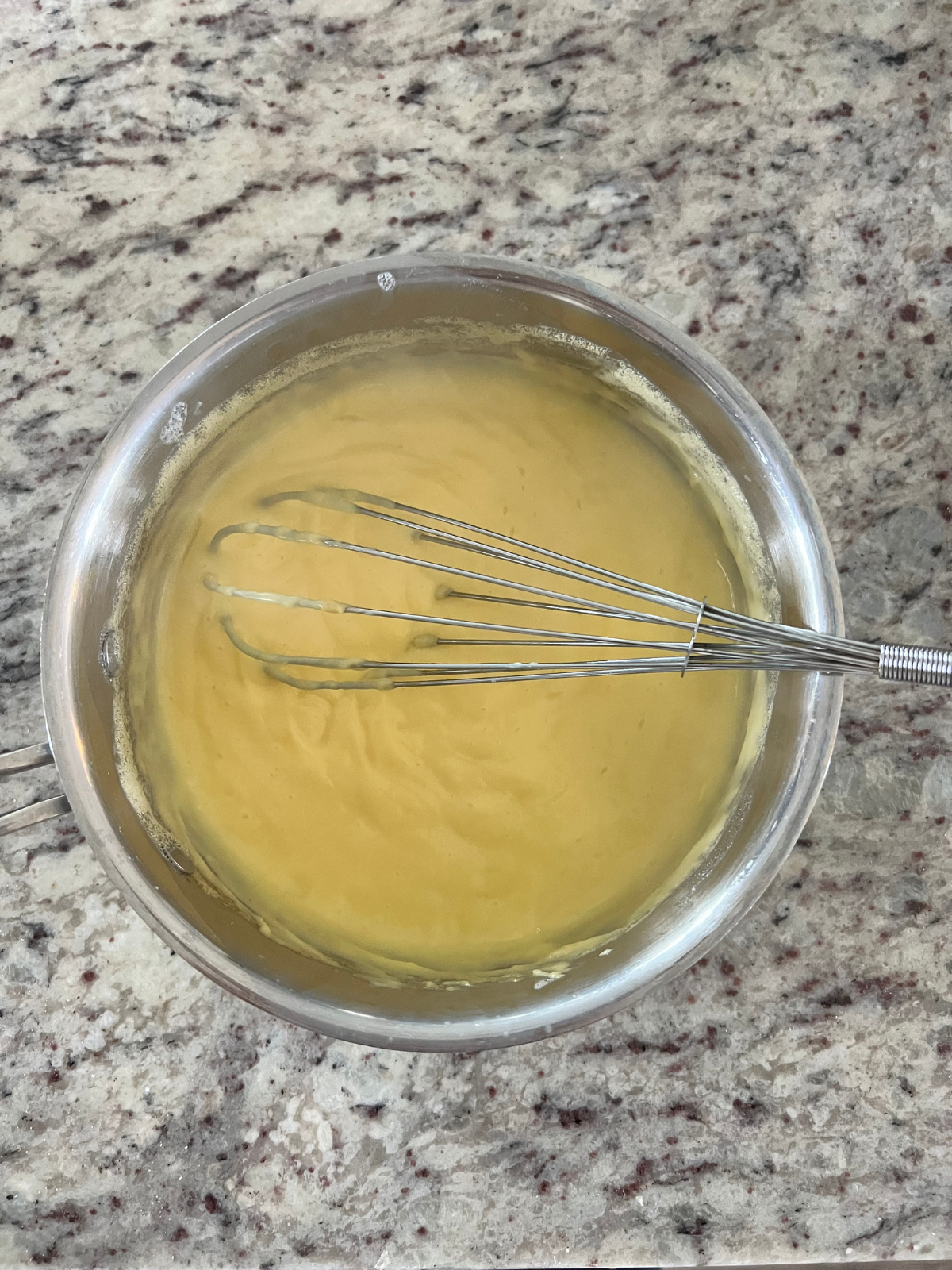 The vanilla custard is shown in a saucepan. A whisk sits in the saucepan.