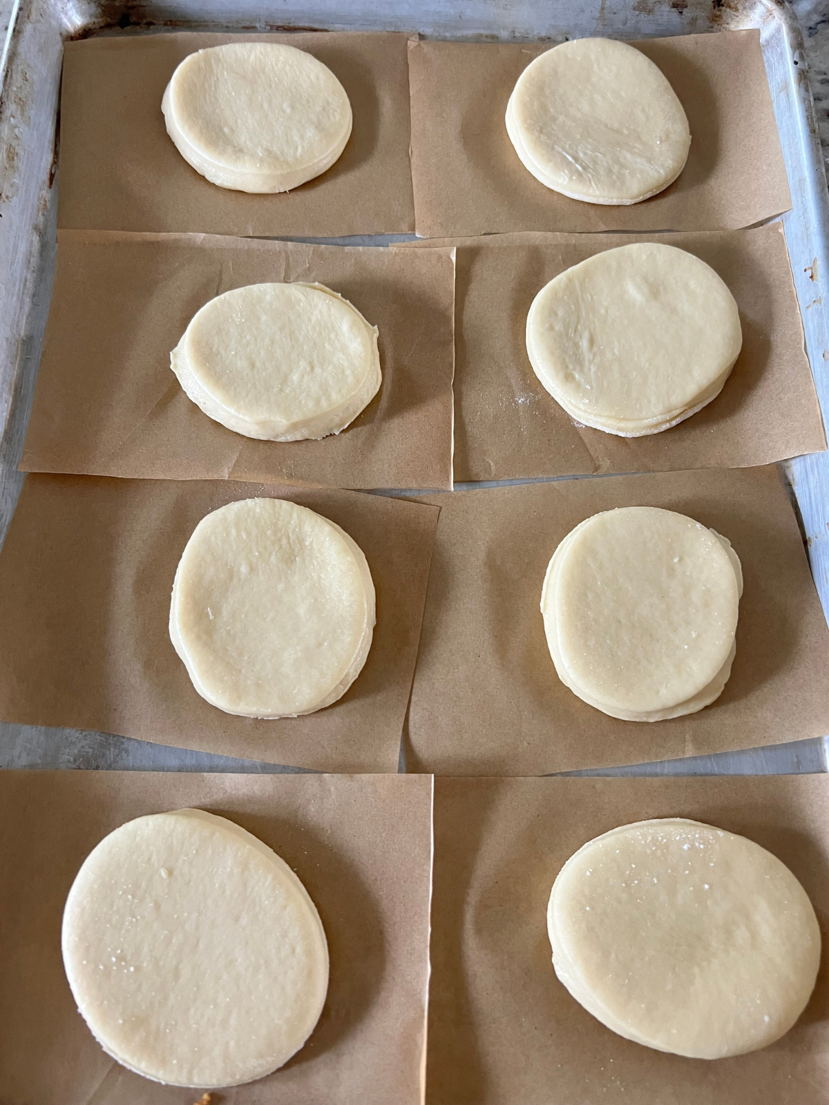 The sourdough brioche donuts have been shaped and are preparing for their second rise on individual parchment paper squares.