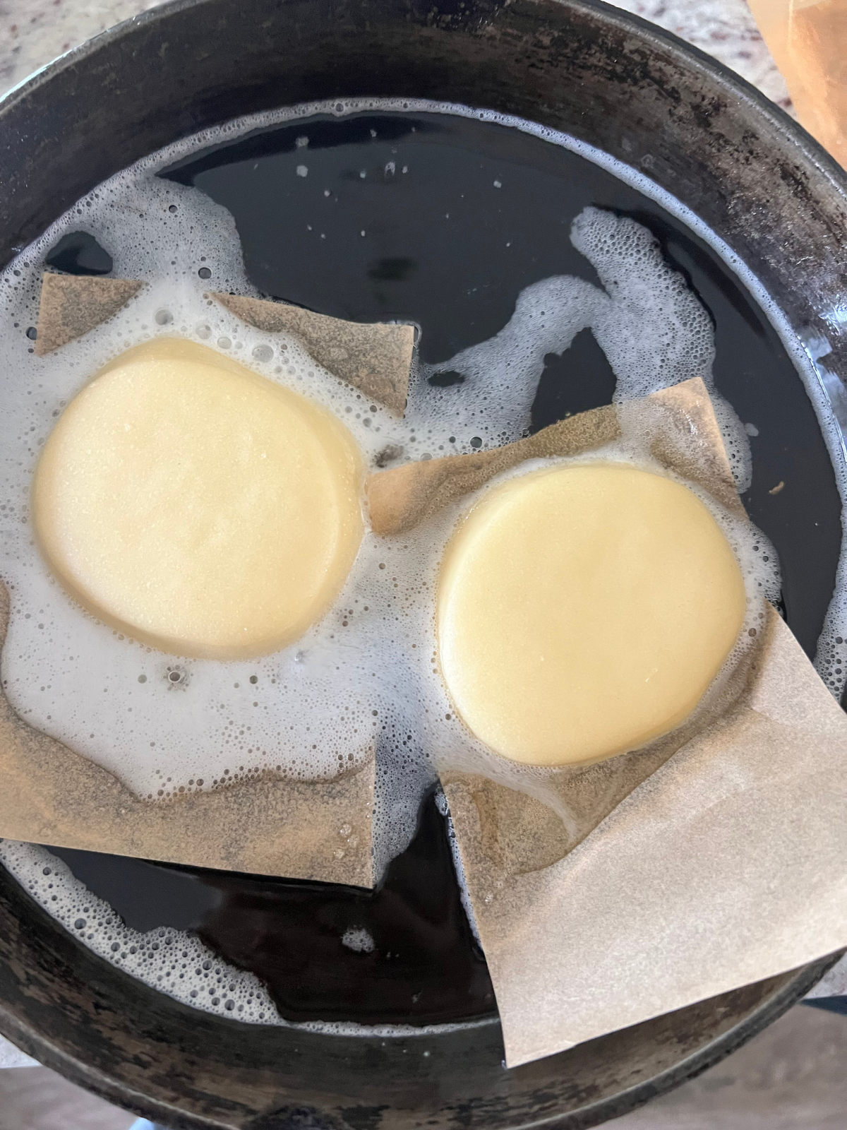 The sourdough brioche donuts are frying in coconut oil in a cast iron pan.