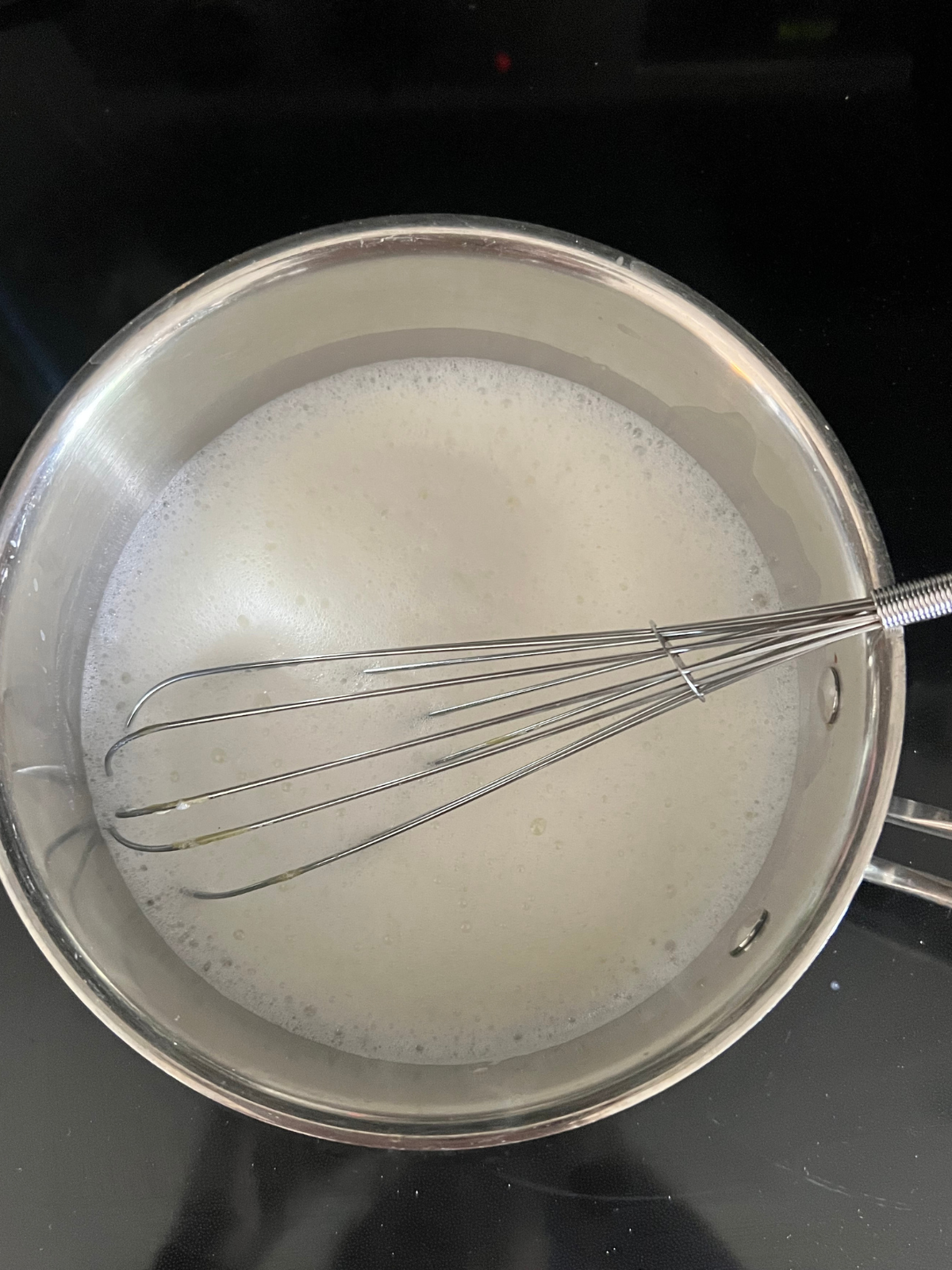 The milk and sugar mixture is heating up in the saucepan on the stove.